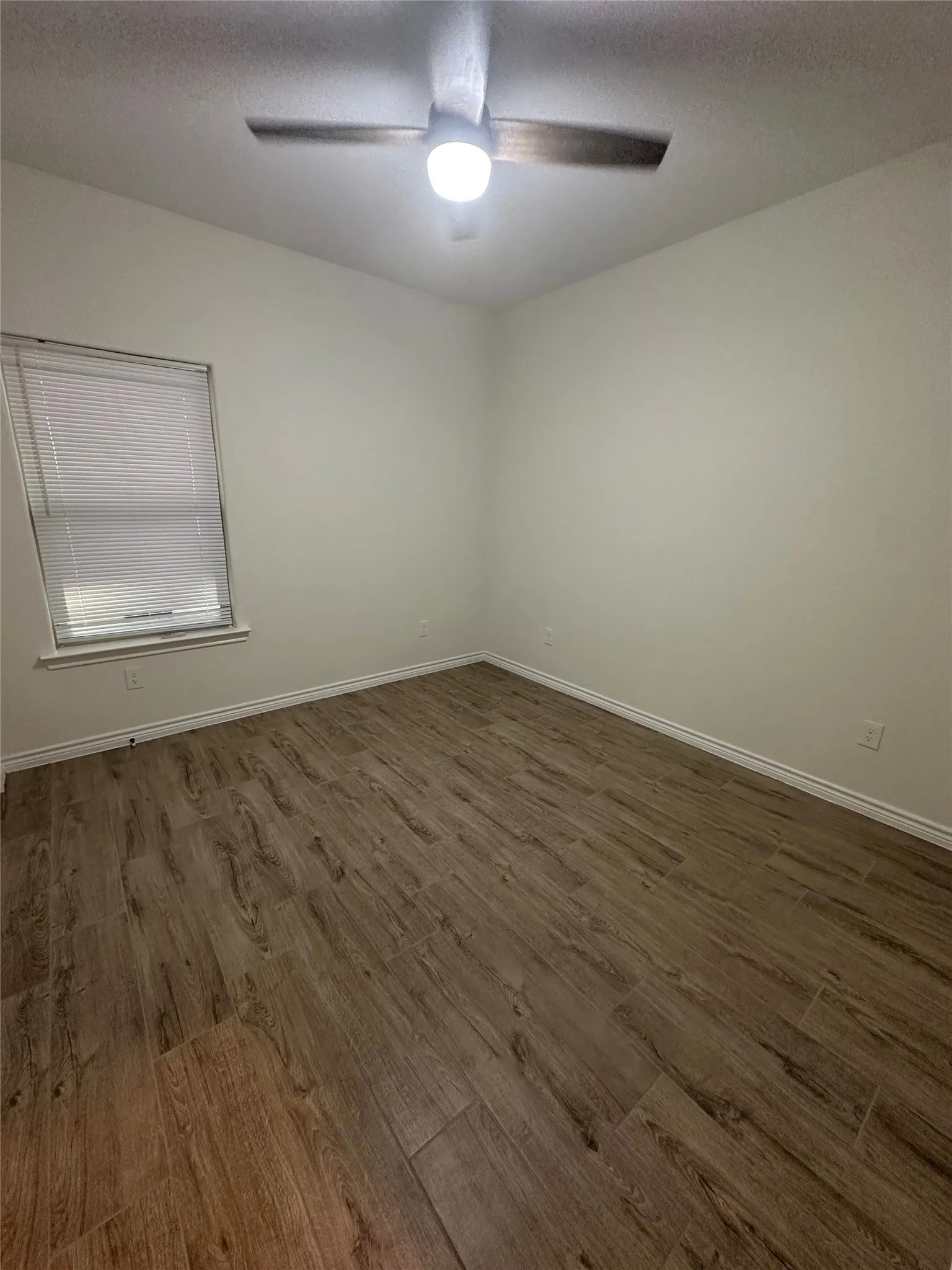 Wood-finish flooring, neutral wall tones, and a ceiling fan with integrated lighting
