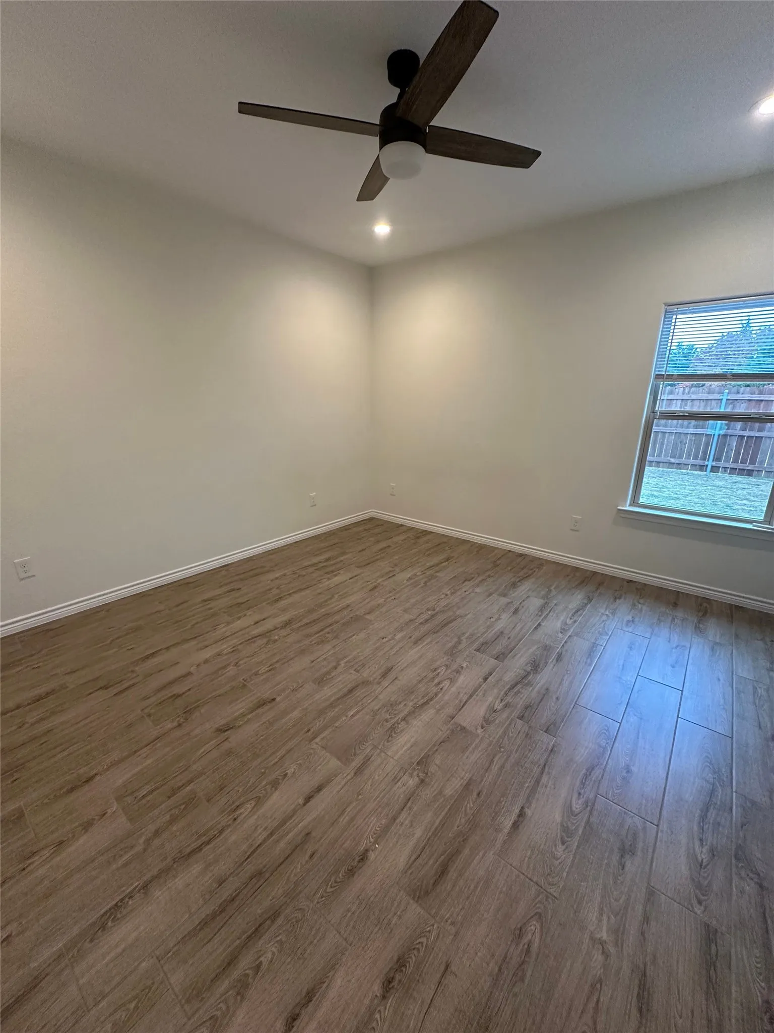 Wood-finish flooring, recessed lighting, ceiling fan, window with blinds
