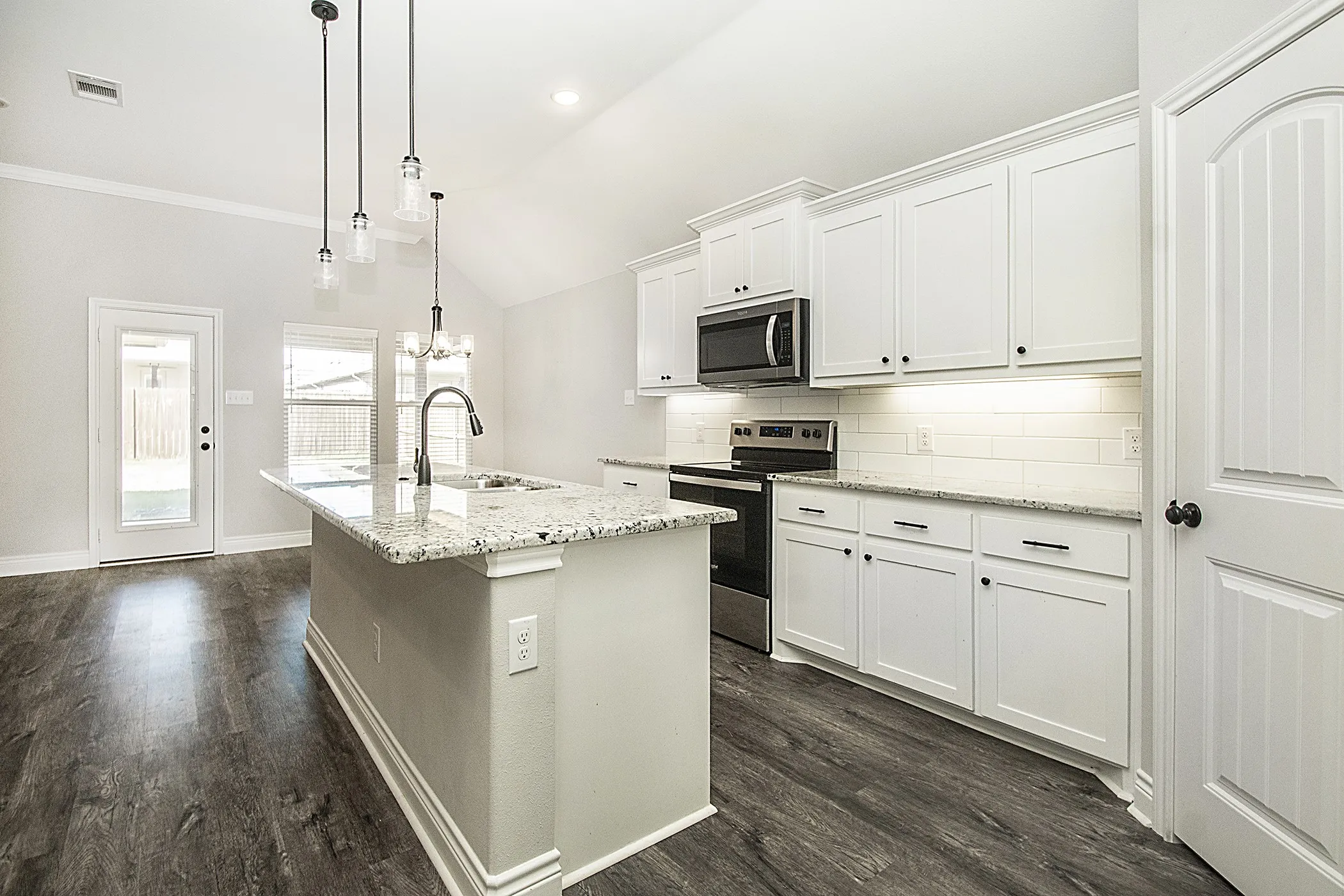 Kitchen featuring a center island with granite-style countertop, stainless steel appliances, white cabinetry, and wood-finish flooring