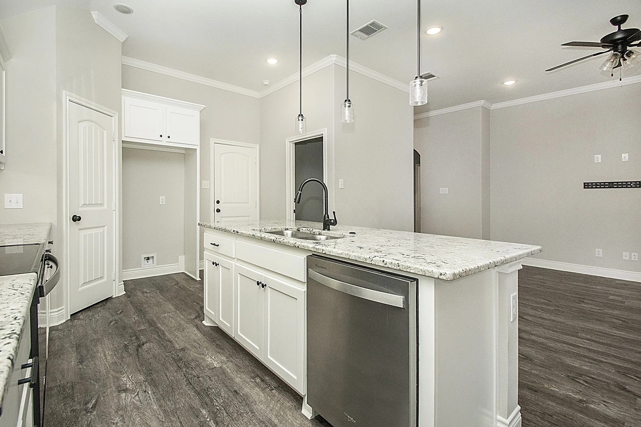 Kitchen island featuring a stainless steel dishwasher, dual basin sink, and pendant lighting