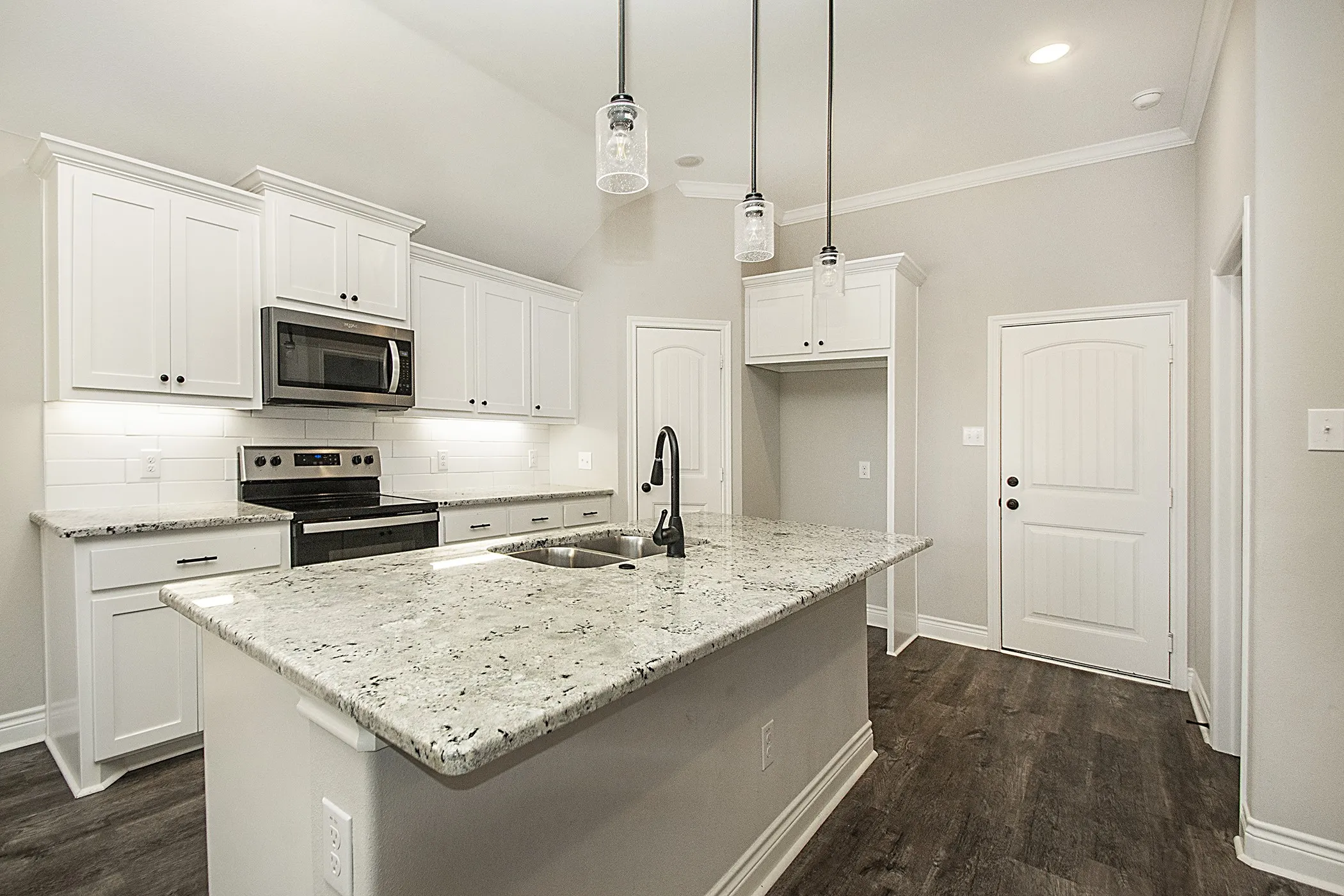Kitchen featuring white cabinetry, granite countertops, stainless steel appliances, a tile backsplash, and dark wood-finish flooring