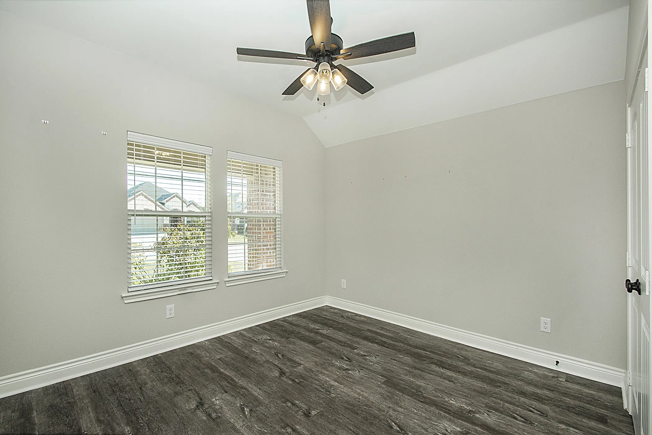 Vaulted ceiling with a ceiling fan, wood-finish flooring, and dual windows with blinds