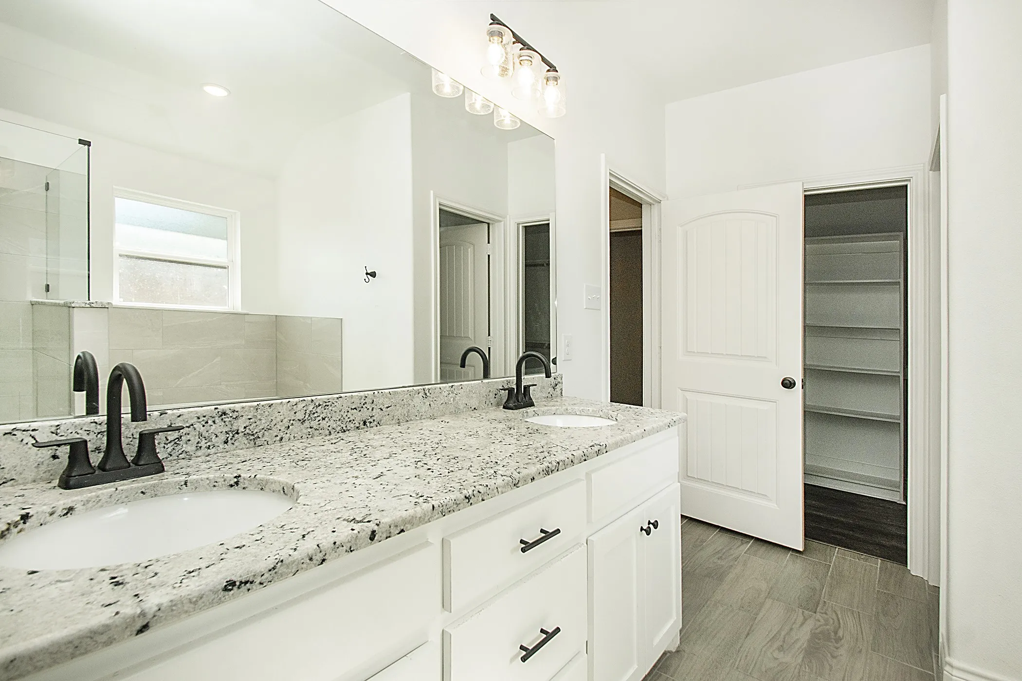 Double vanity with speckled countertop and matte black fixtures