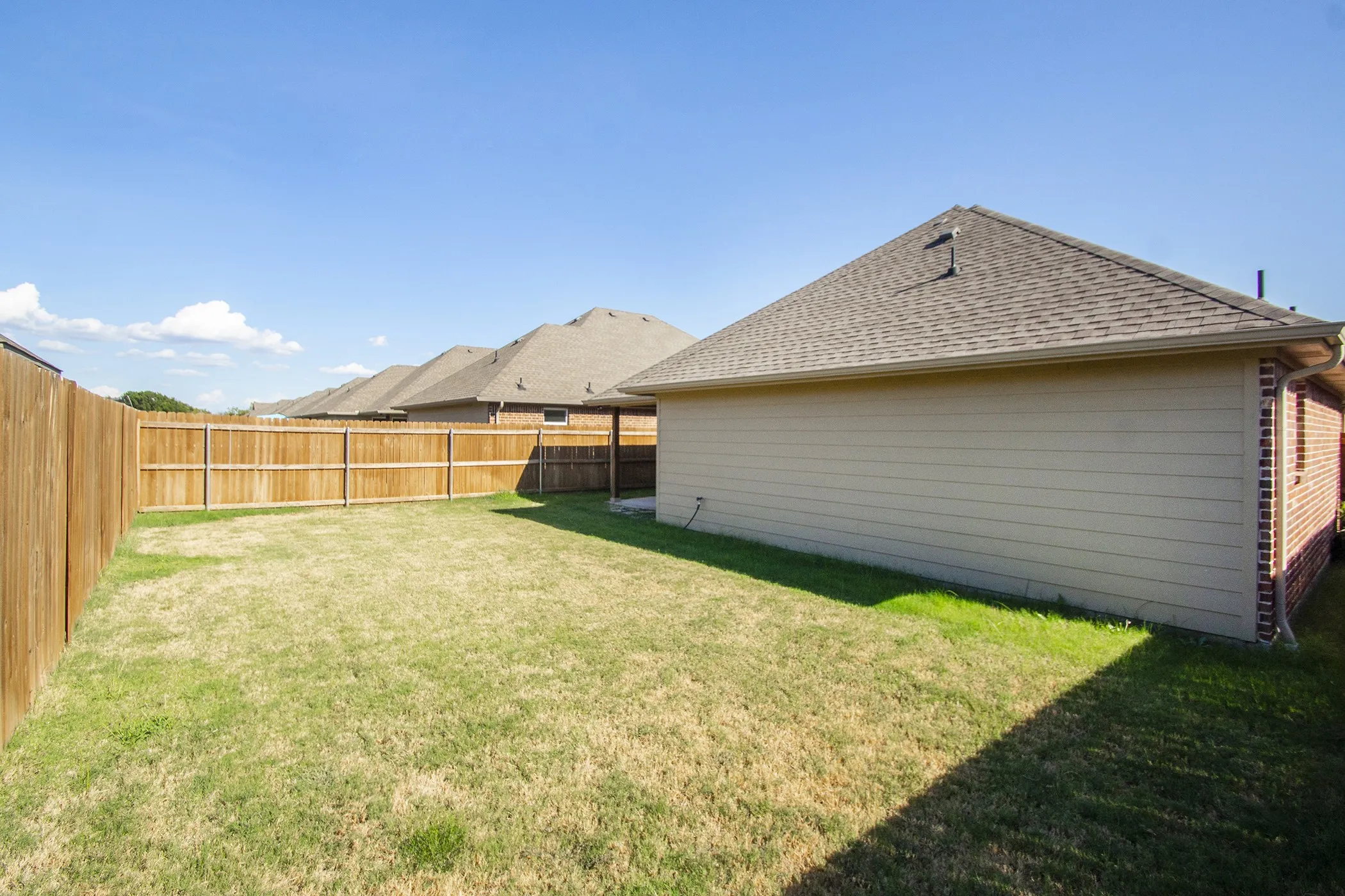 Expansive grassy yard with a wood privacy fence