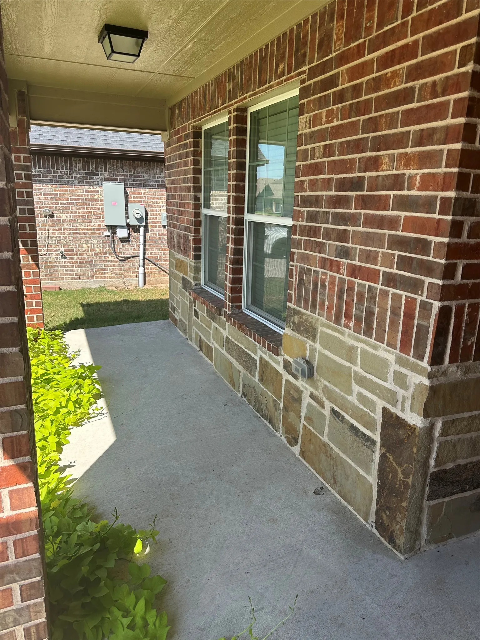 Brick and stone veneer exterior with double-hung windows, concrete walkway, and covered entryway