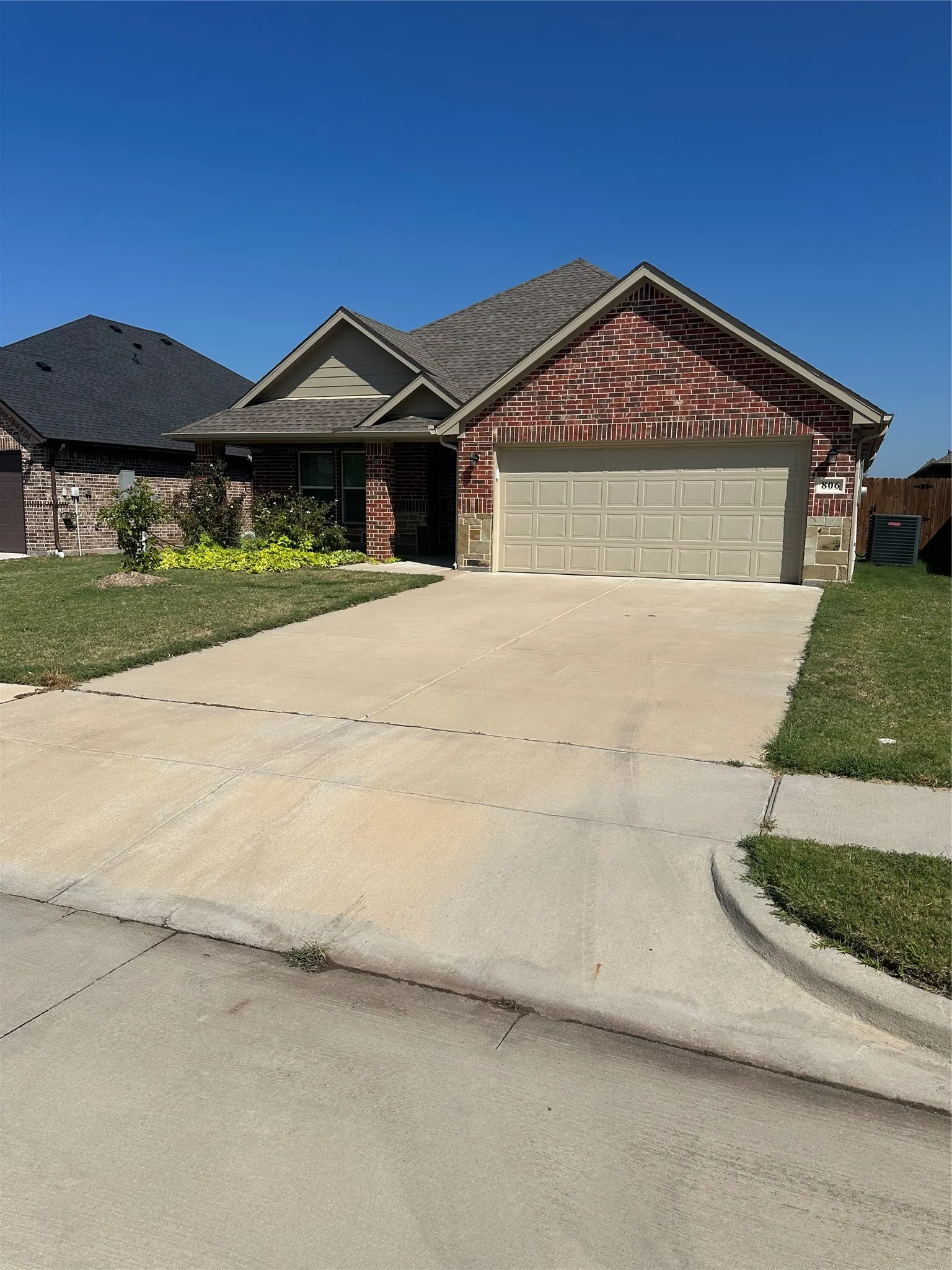 Brick exterior with stone accents, an attached garage, and a concrete driveway