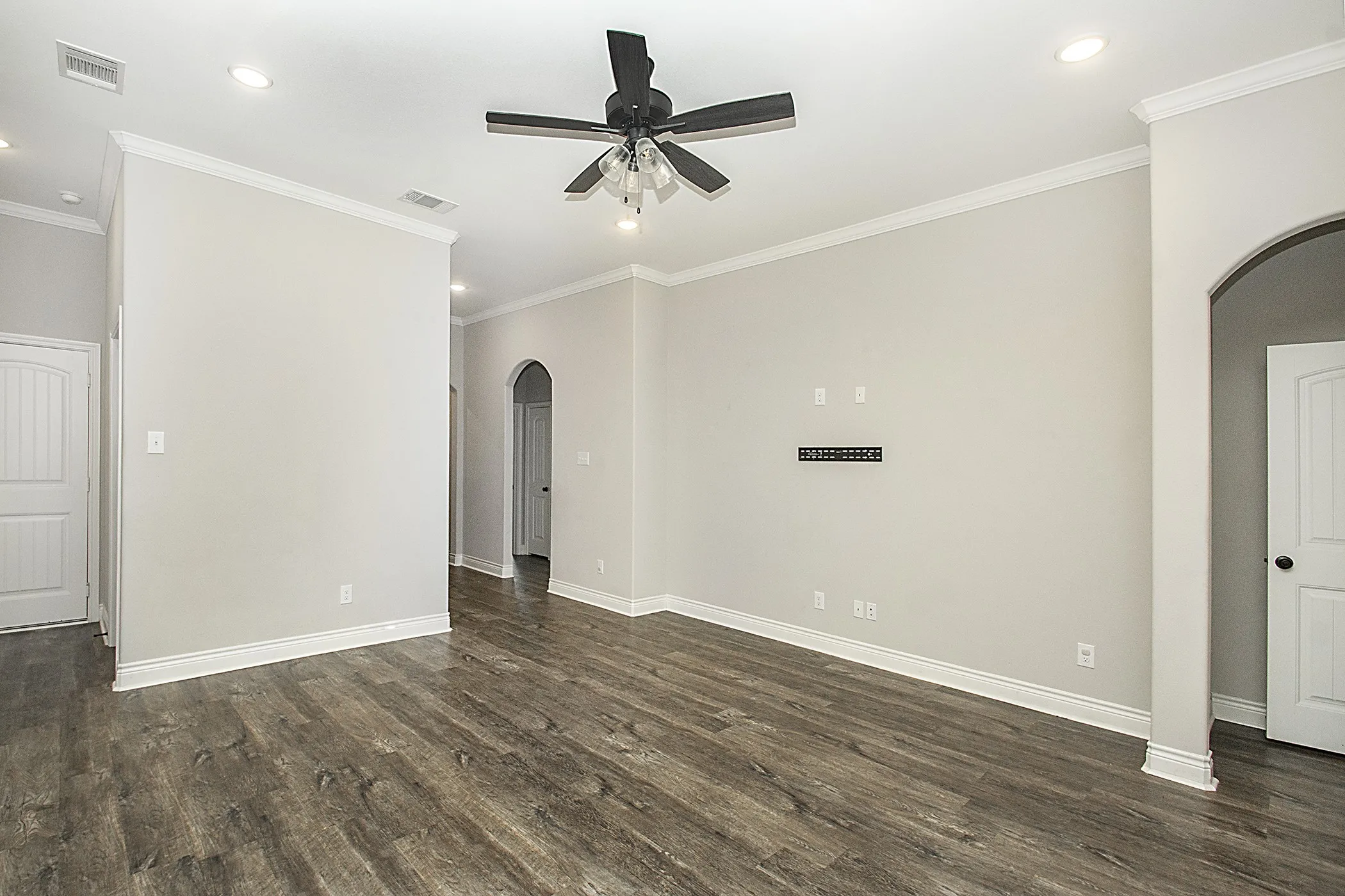 Expansive living area with wood-finish flooring, recessed lighting, and crown molding