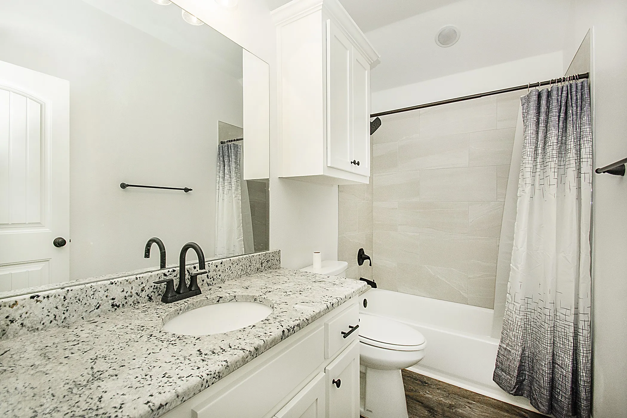 White vanity with a speckled countertop, undermount sink, and matte black faucet