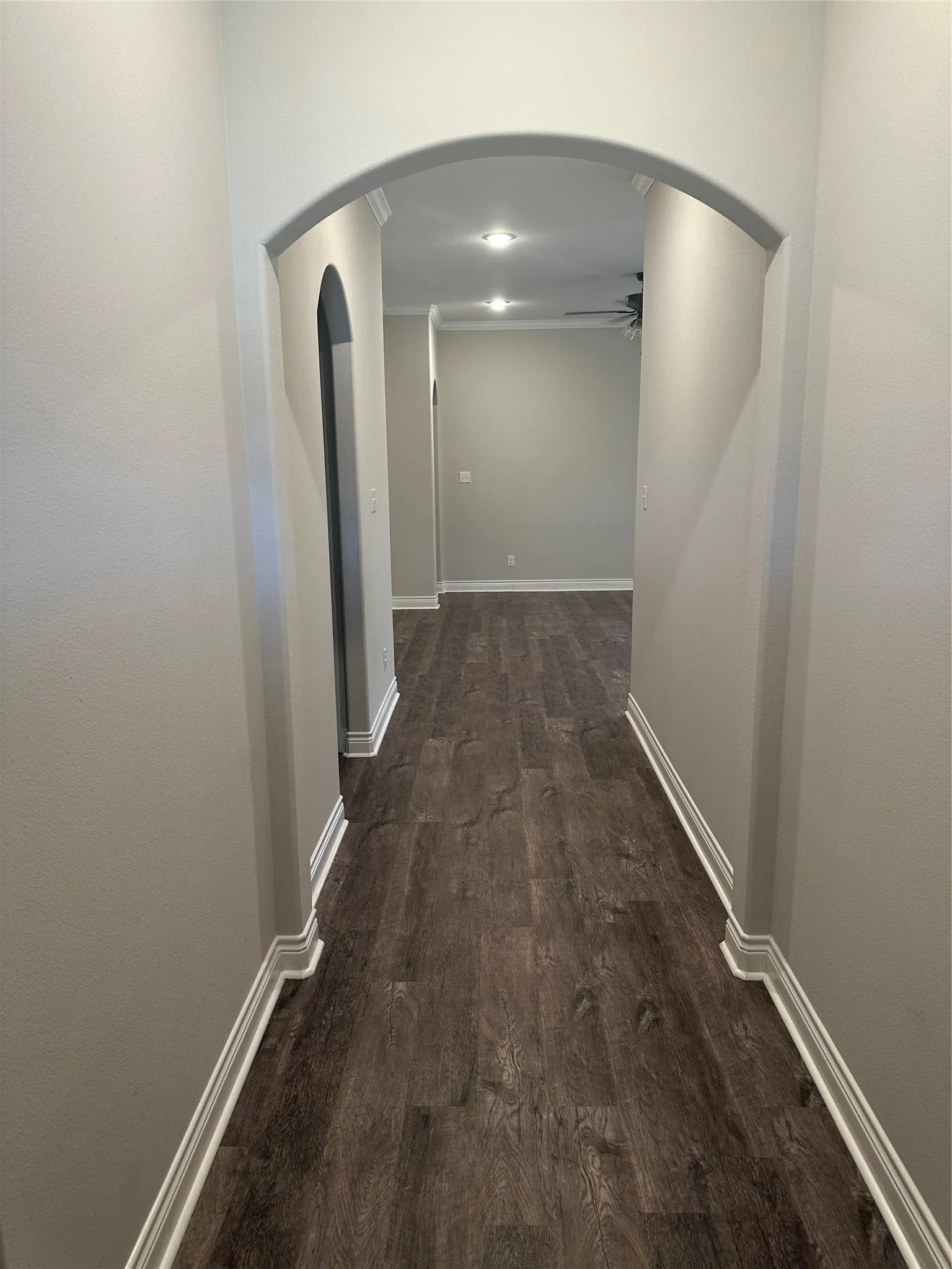 Archway entry with wood-finish flooring, recessed lighting, and crown molding