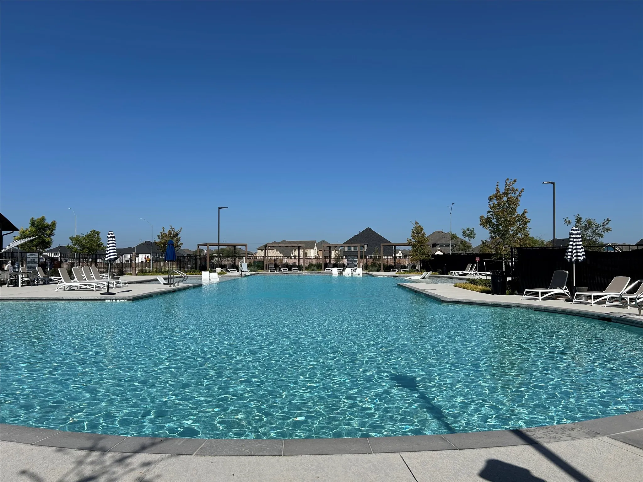 Expansive community pool with integrated lounging areas and surrounding paved decking