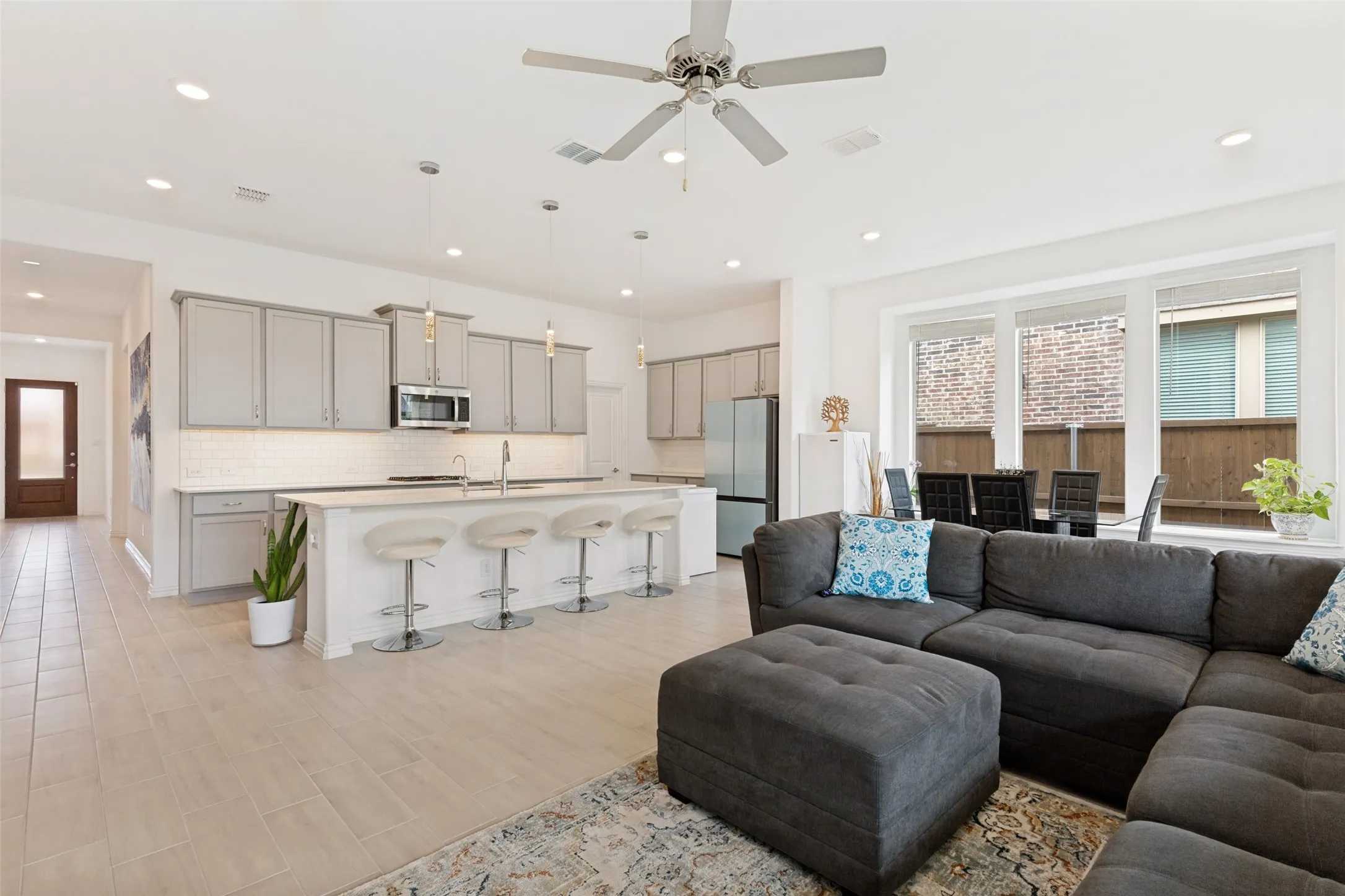 Open-concept living space with tile flooring, recessed lighting, a ceiling fan, and large windows