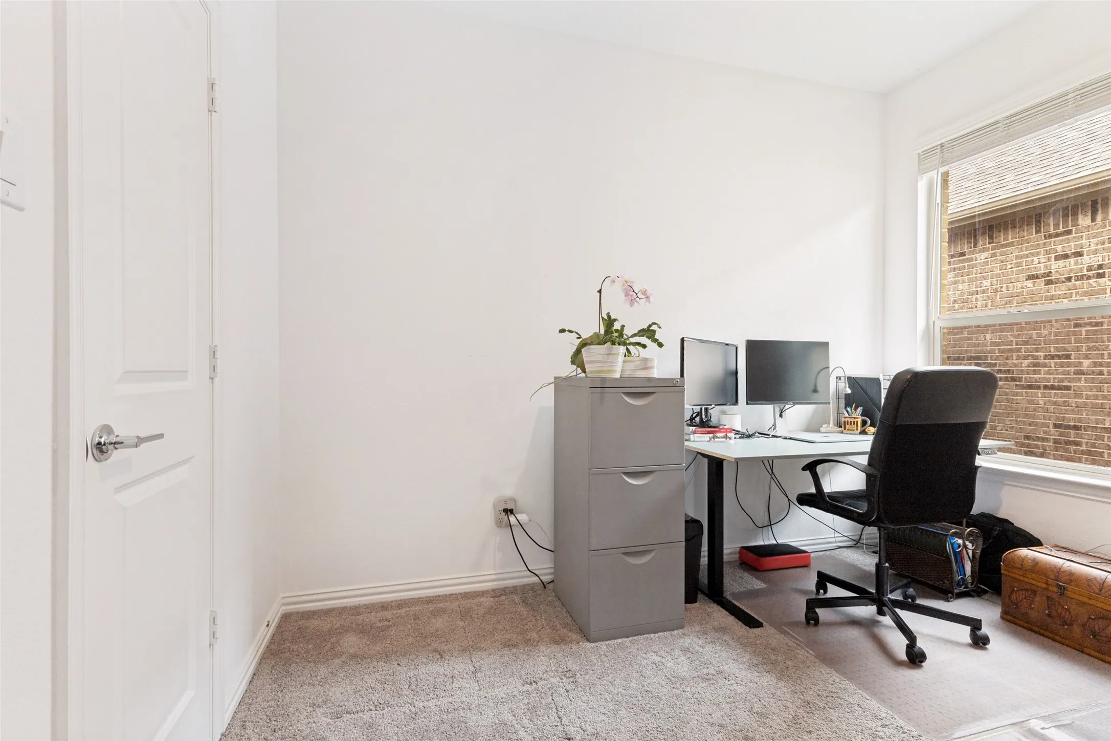 Neutral wall color with carpeted flooring, a panel door with lever hardware, and a window with horizontal blinds