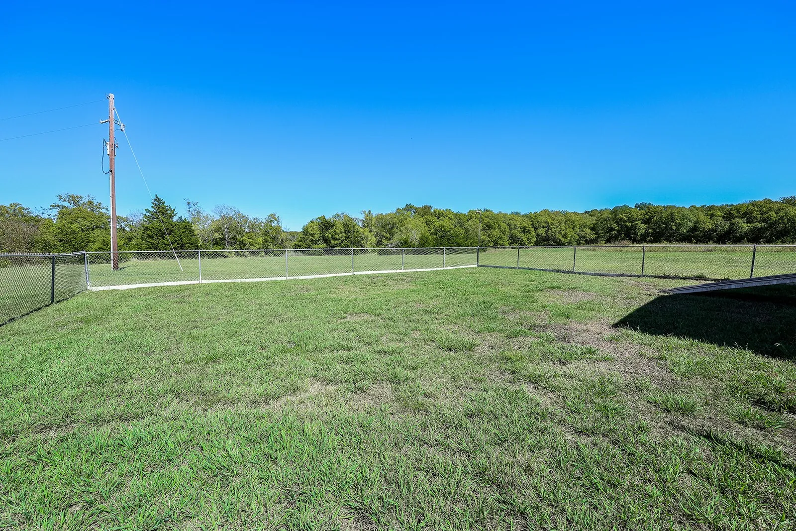 Expansive grassy area with chain link fencing