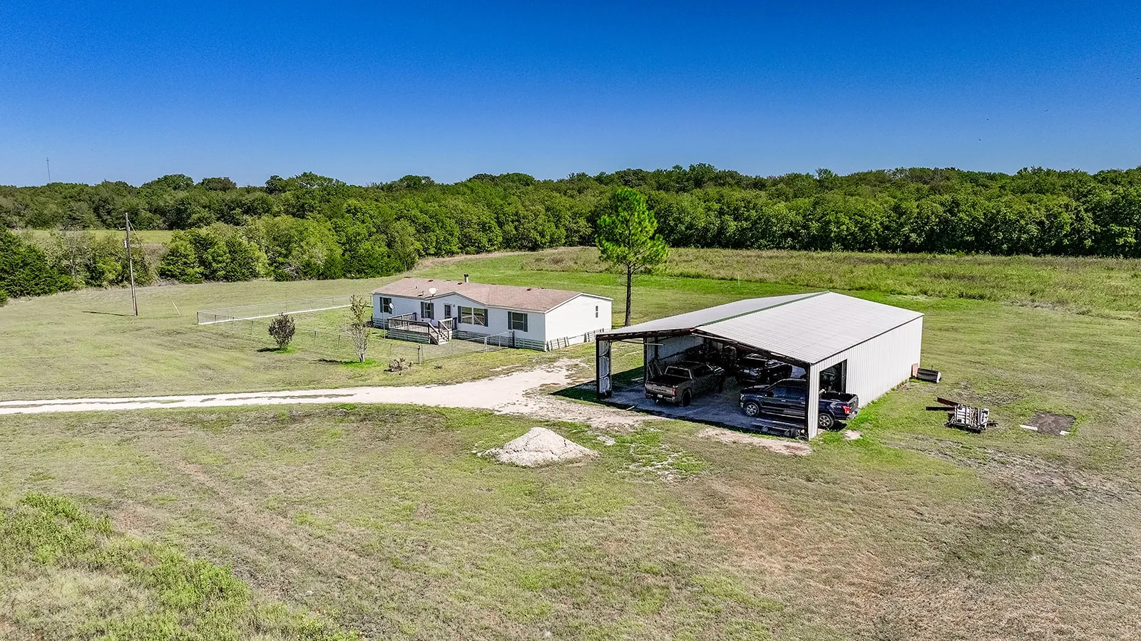 Spacious lot featuring a single-story residence with a covered porch and an expansive detached metal outbuilding