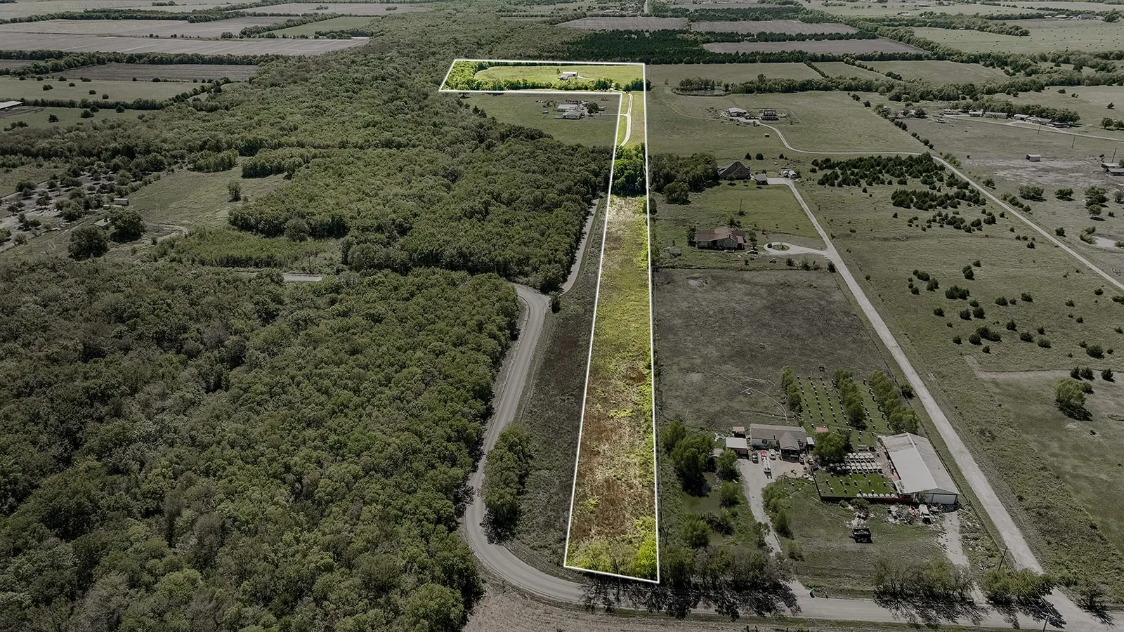 Expansive land parcel featuring a mix of open fields and densely wooded areas