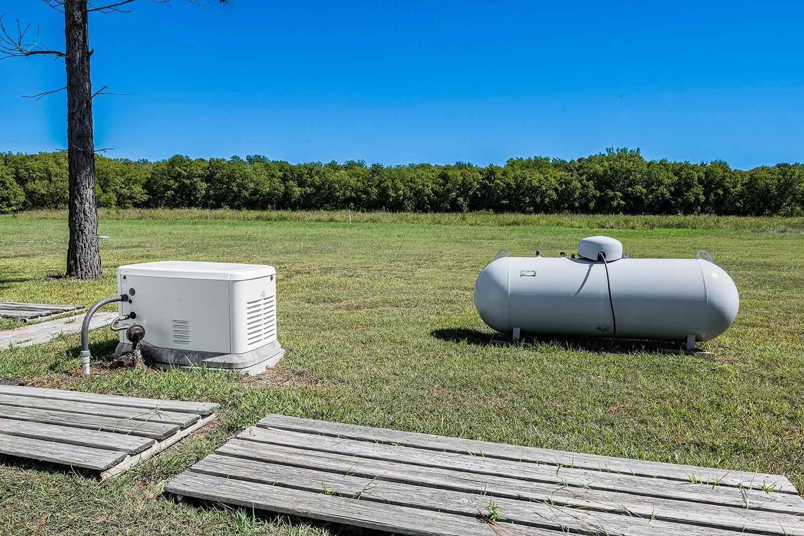 Standby generator and propane tank on a grassy expanse