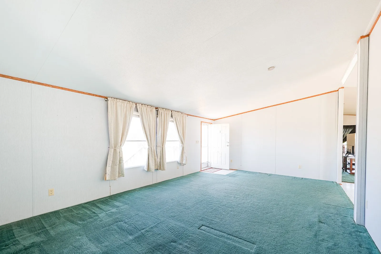 Green carpeting with three windows and white window treatments