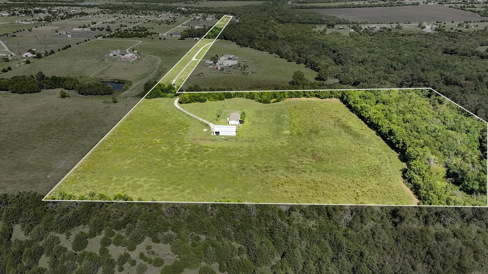 Expansive property featuring a mix of open grassy areas and mature tree lines