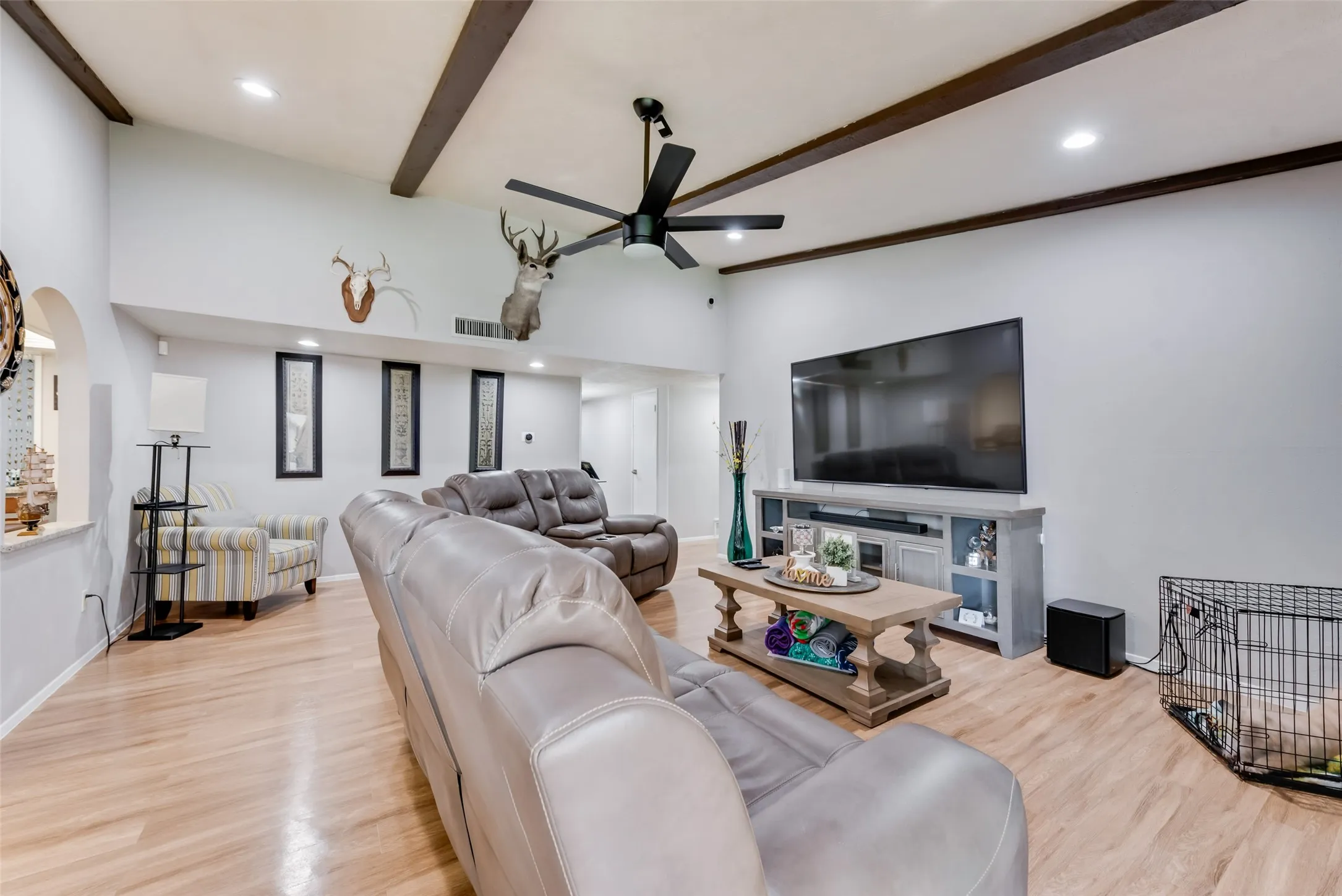 Living room featuring beamed ceiling, light wood-style flooring, recessed lighting, a ceiling fan, and arched walkways