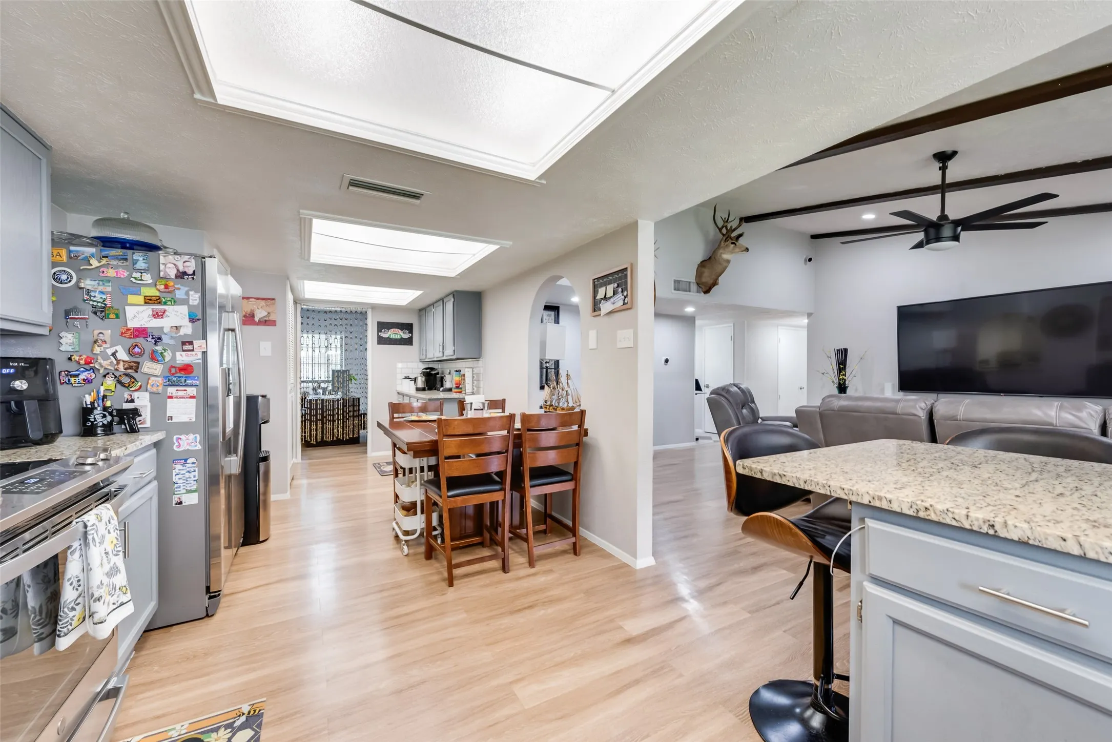 Kitchen featuring gray cabinetry, open floor plan, light wood-style flooring, arched walkways, and electric range