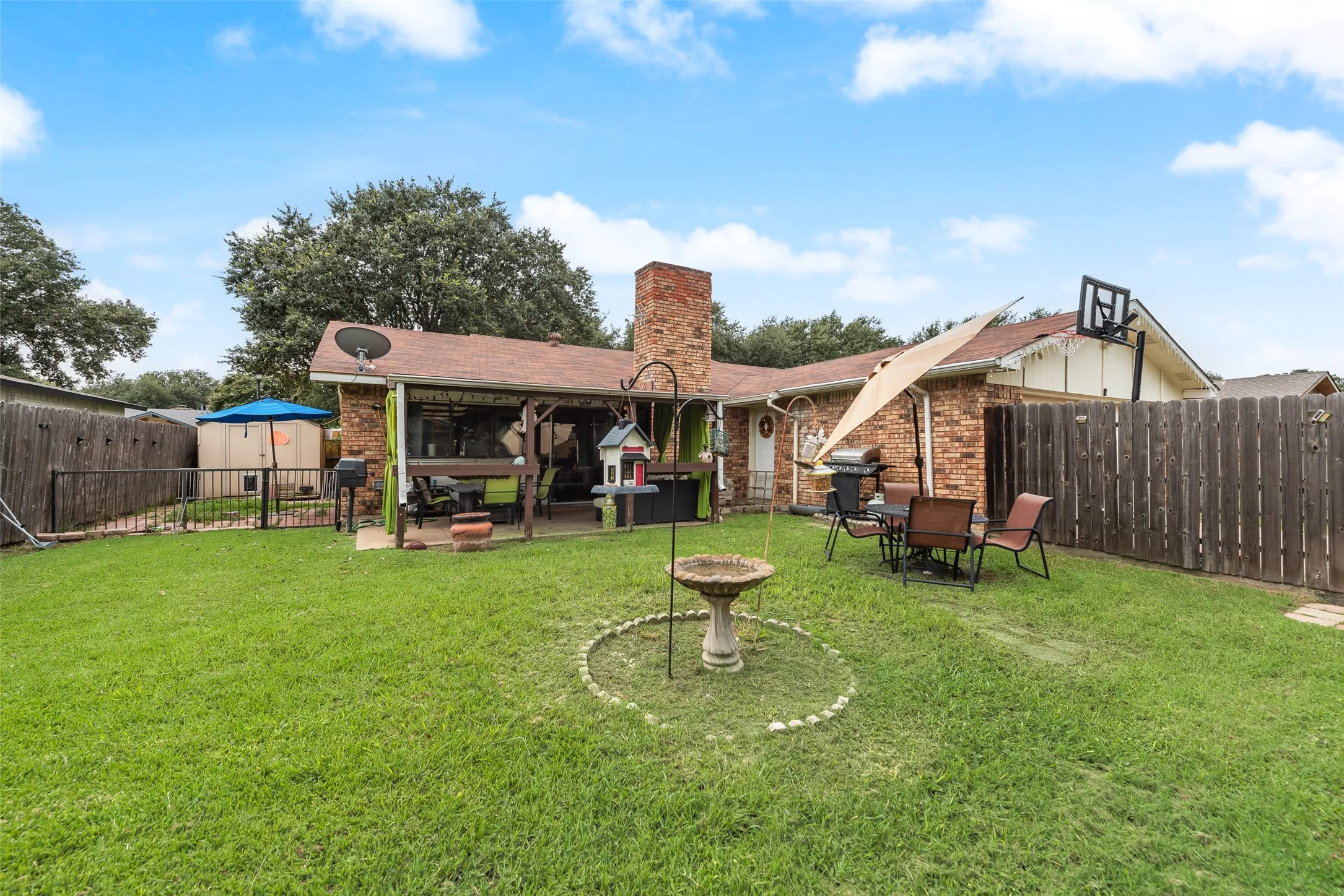 Rear view of property with a fenced backyard, a patio area, brick siding, and a chimney