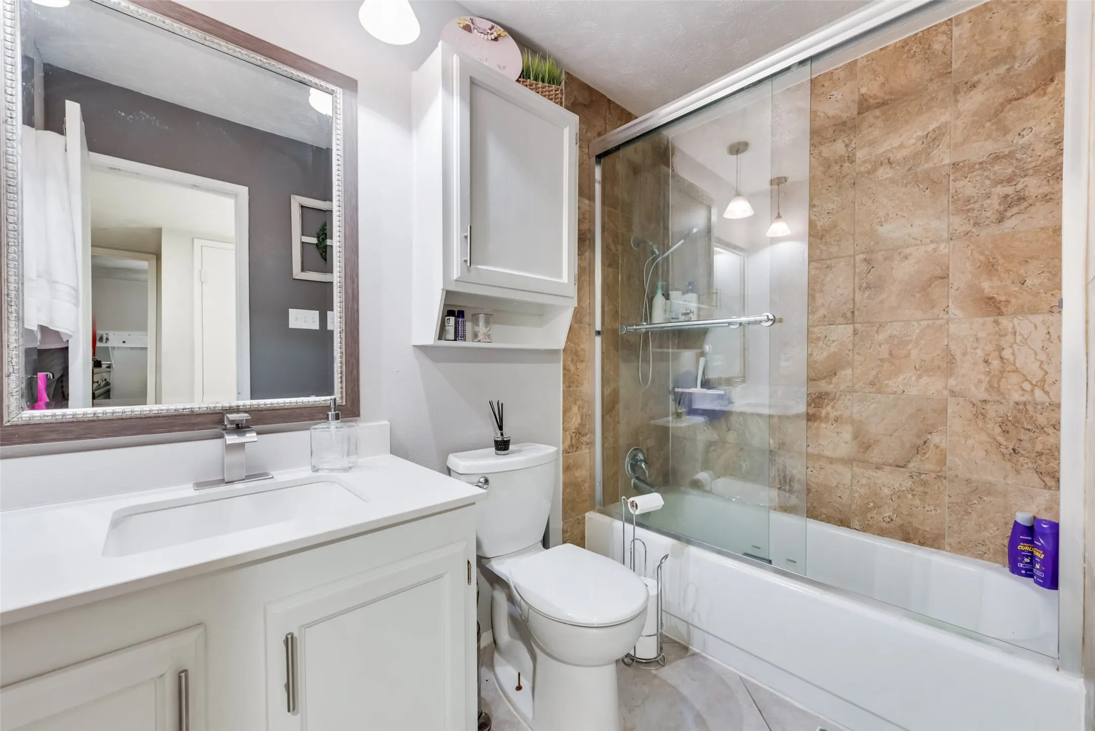 Bathroom featuring combined bath / shower with glass door and vanity