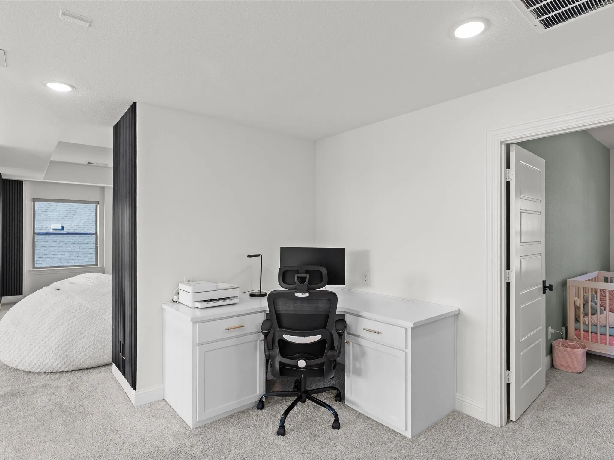 Built-in white desk with cabinetry, recessed lighting, and light-colored carpeting