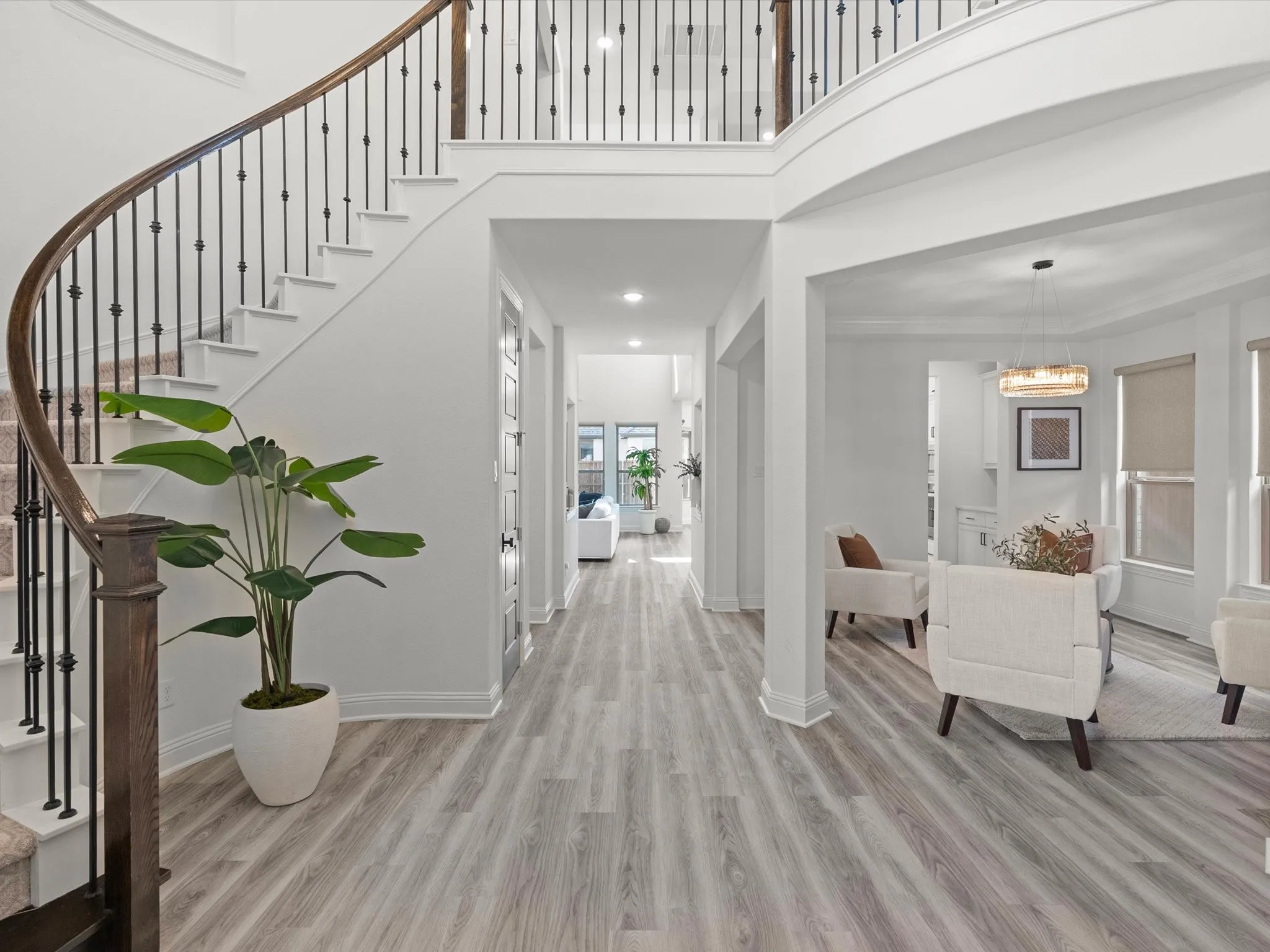 Curved staircase with wood-finish handrail and iron balusters, wood-finish flooring, two-story foyer, recessed lighting, and a contemporary chandelier