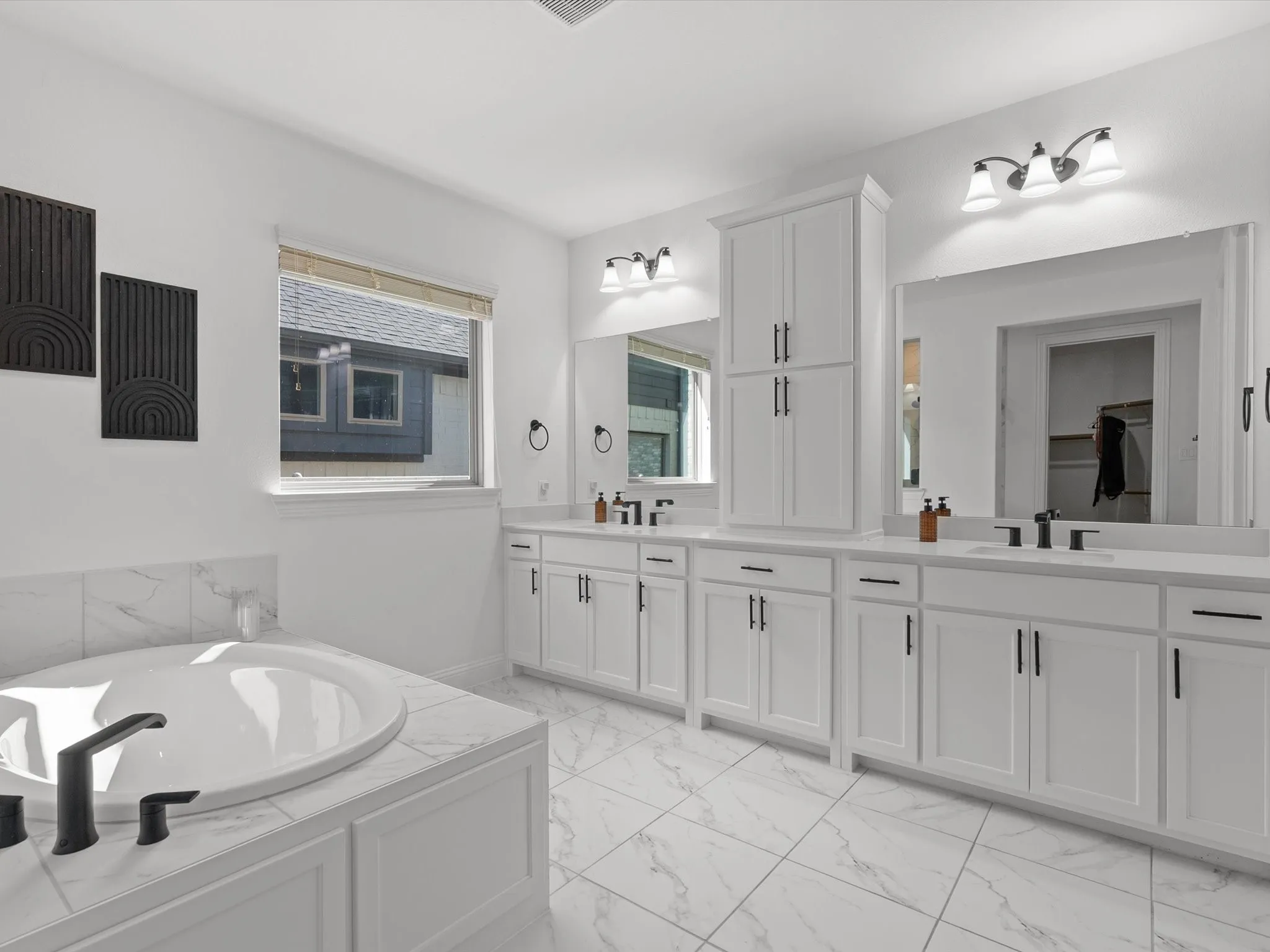 Dual vanity with white cabinetry, matte black hardware, and large mirrors