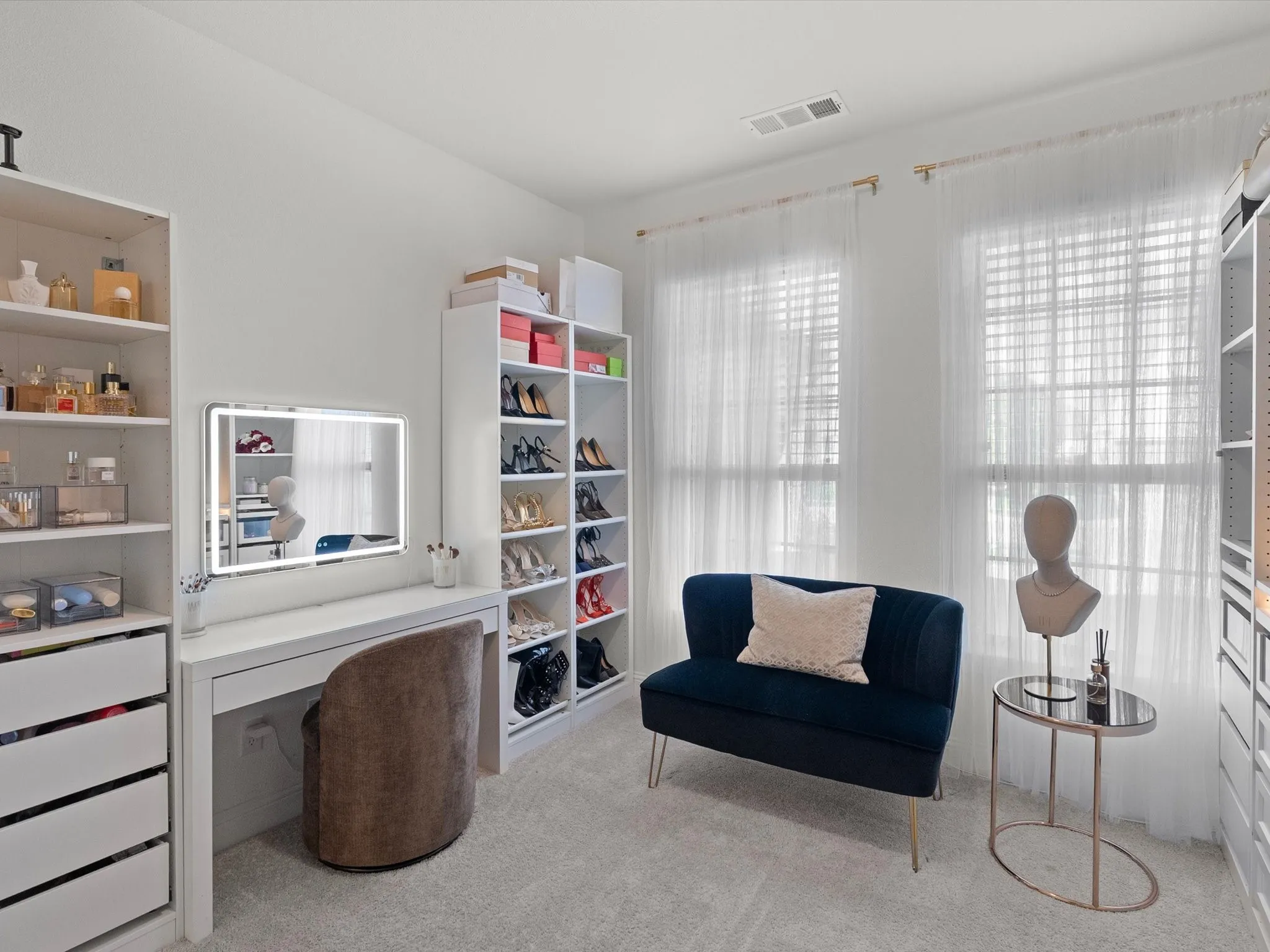 Built-in shelving, vanity station with illuminated mirror, twin windows, and neutral carpeting