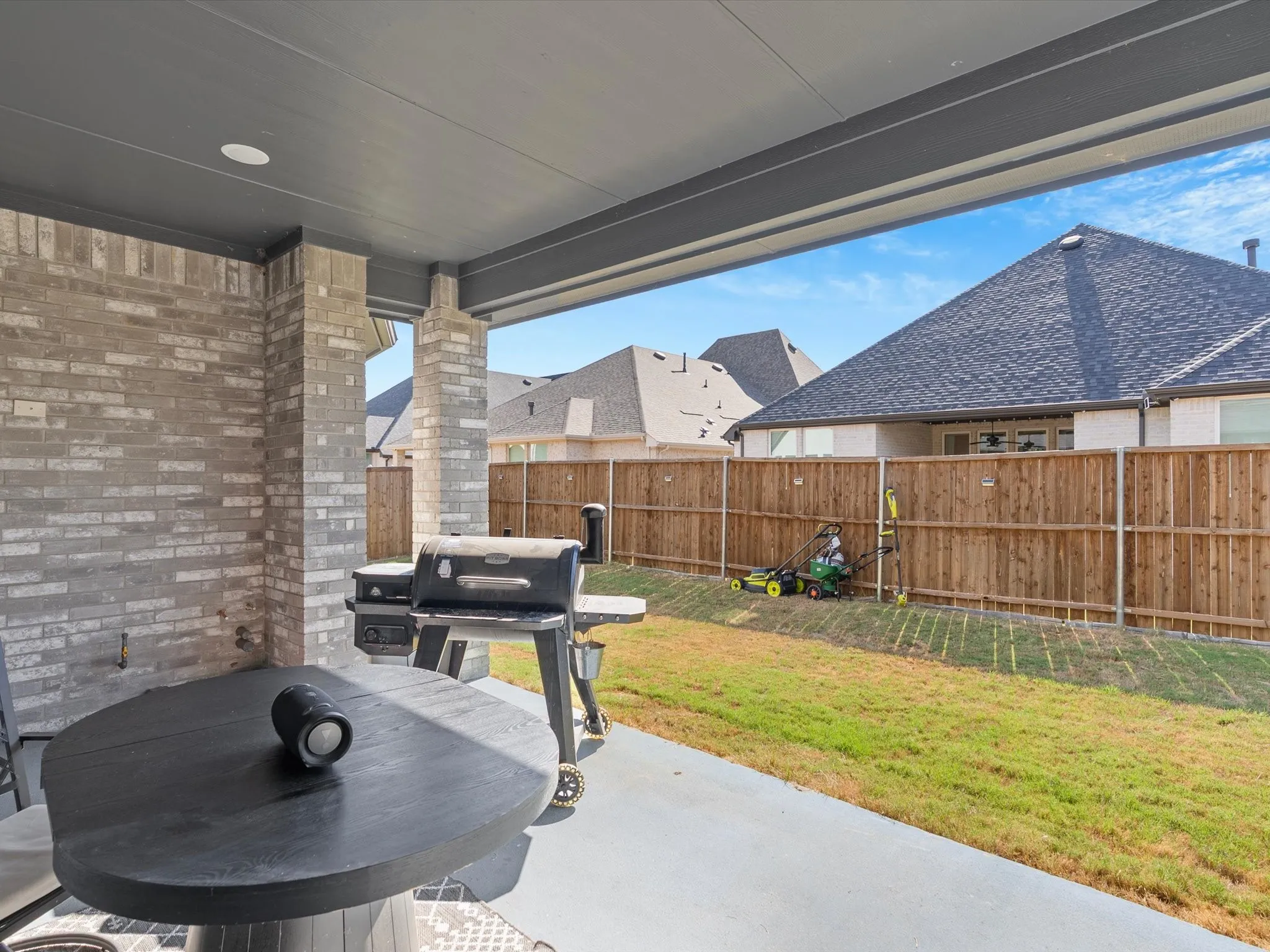 Covered patio with recessed lighting, brick and stone columns, and a concrete slab