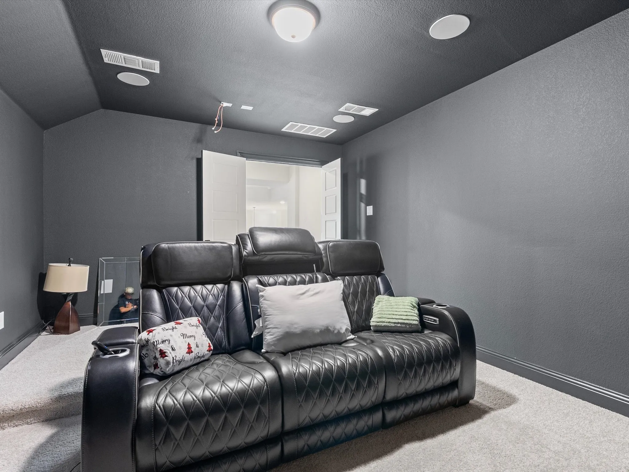 Carpeted interior space with dark painted walls and ceiling, featuring recessed lighting and built-in ceiling speakers