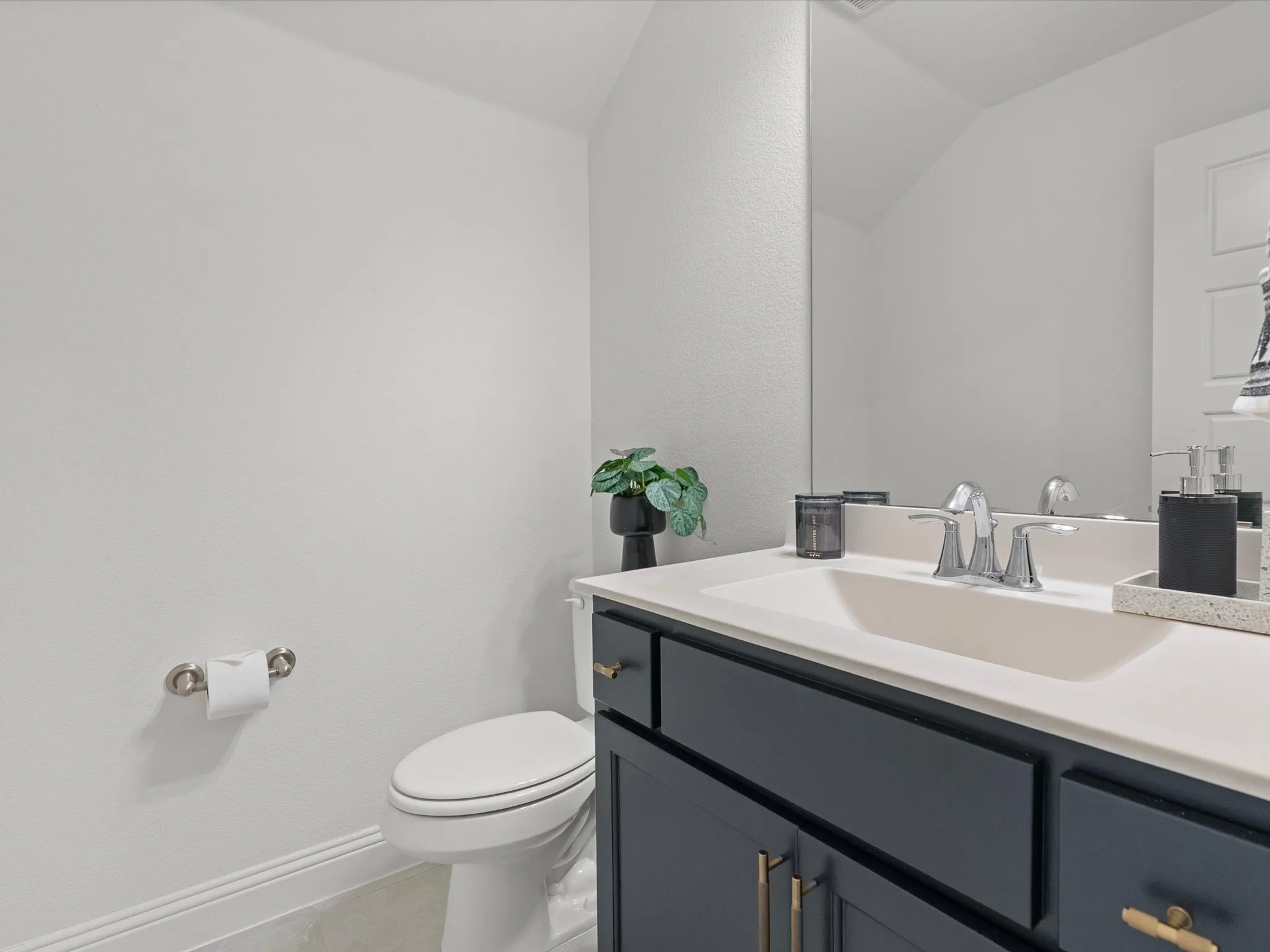 Vanity with an integrated rectangular sink, chrome faucet, and dark cabinetry with gold-tone hardware