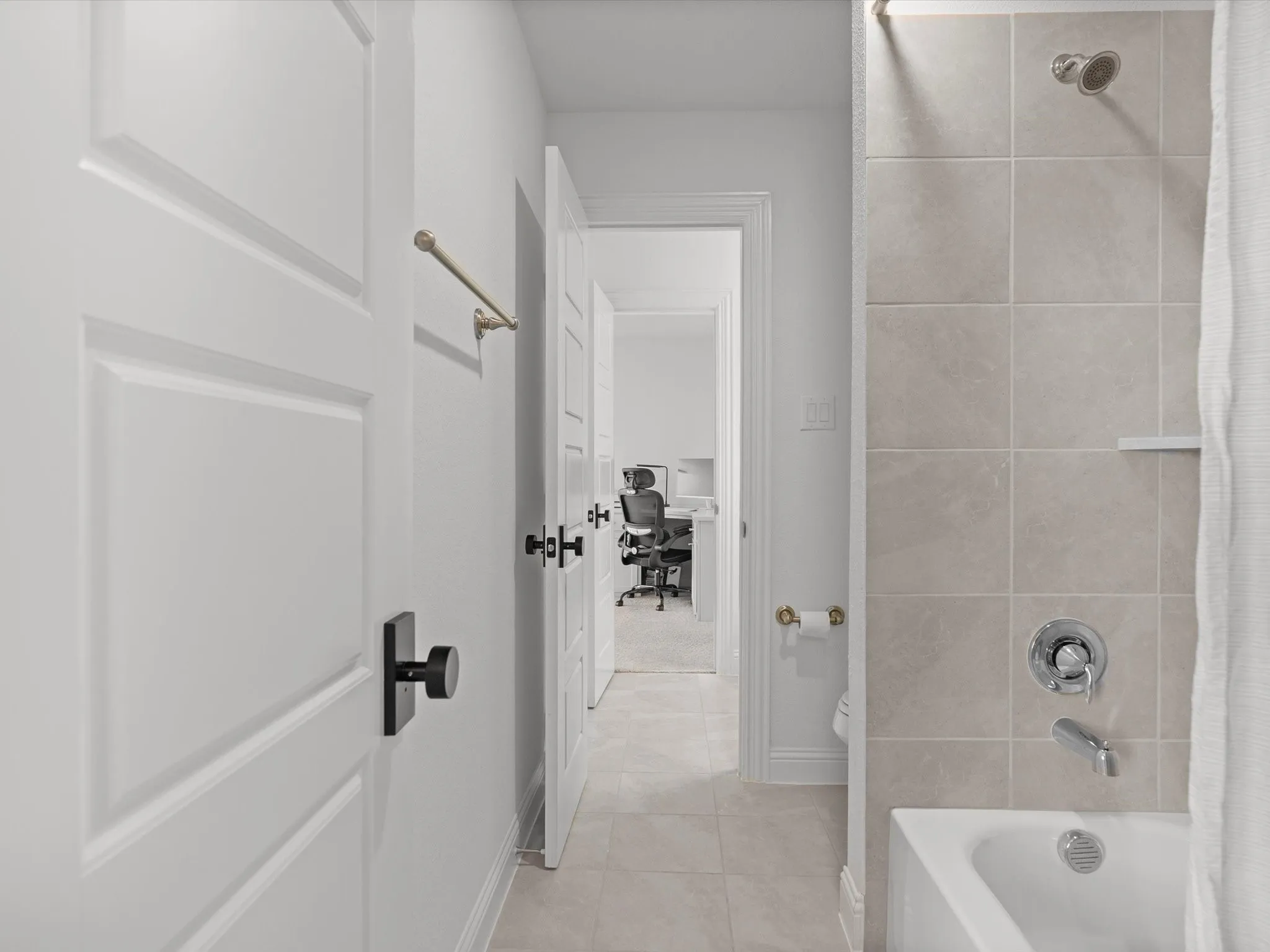 Bathtub with chrome fixtures, tiled shower surround, and a built-in shower shelf