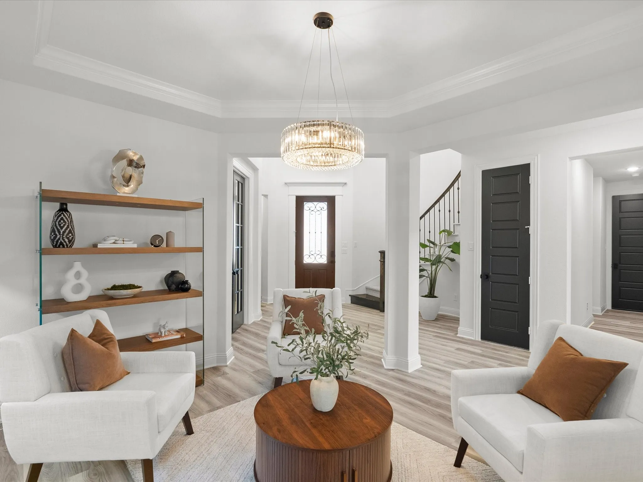 Tray ceiling with crown molding, crystal chandelier, wood-finish flooring, dark paneled doors, and a wood-and-metal shelving unit