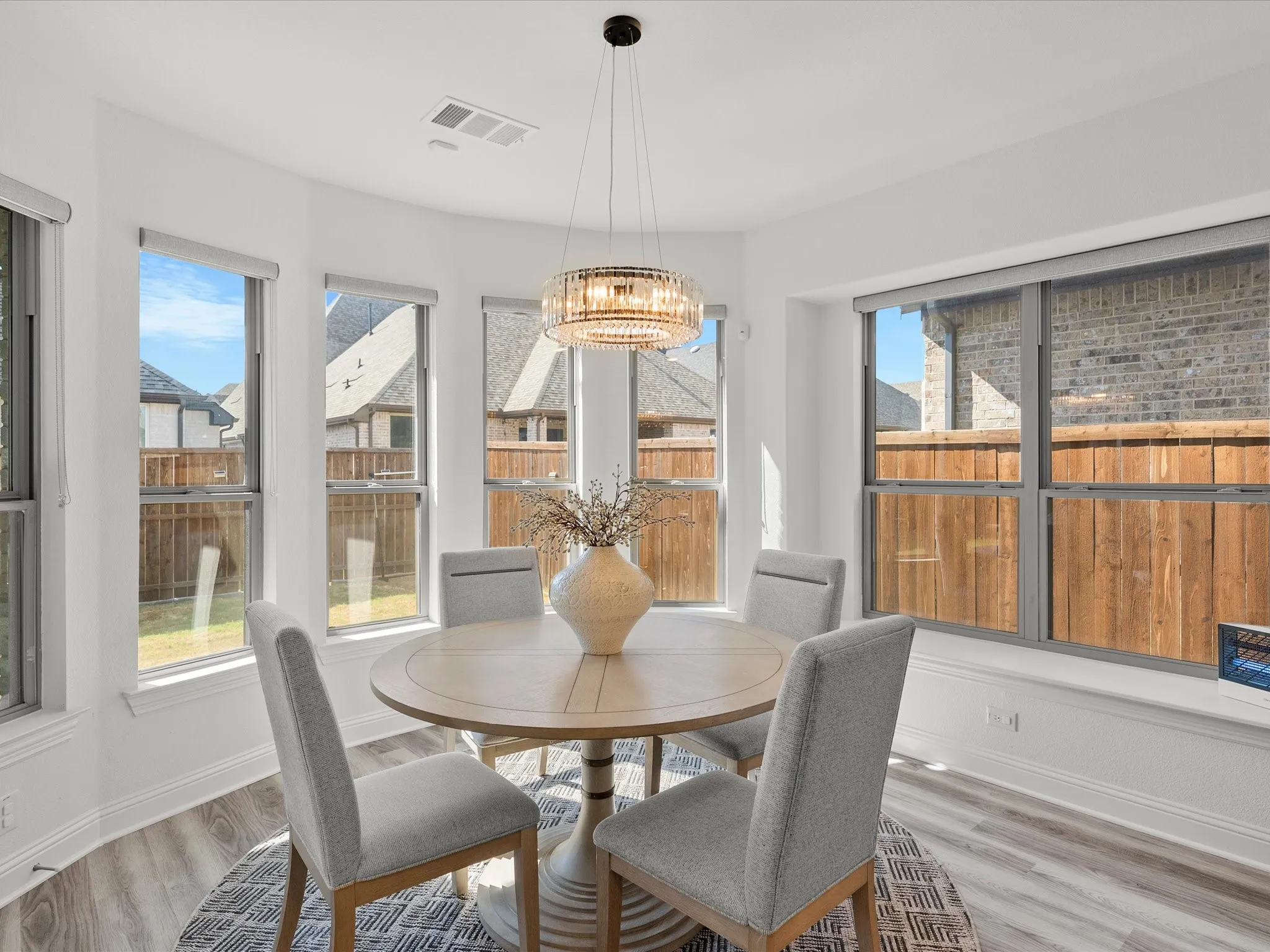 Bay window with multiple windows, wood-finish flooring, and a contemporary chandelier