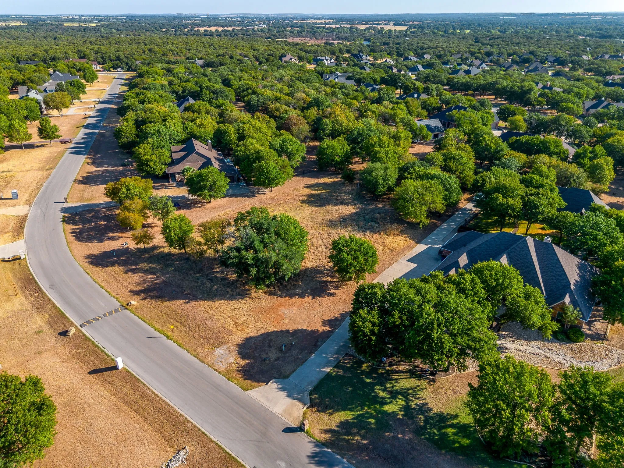 Residential neighborhood featuring mature trees, paved roads, and single-family homes with pitched roofs