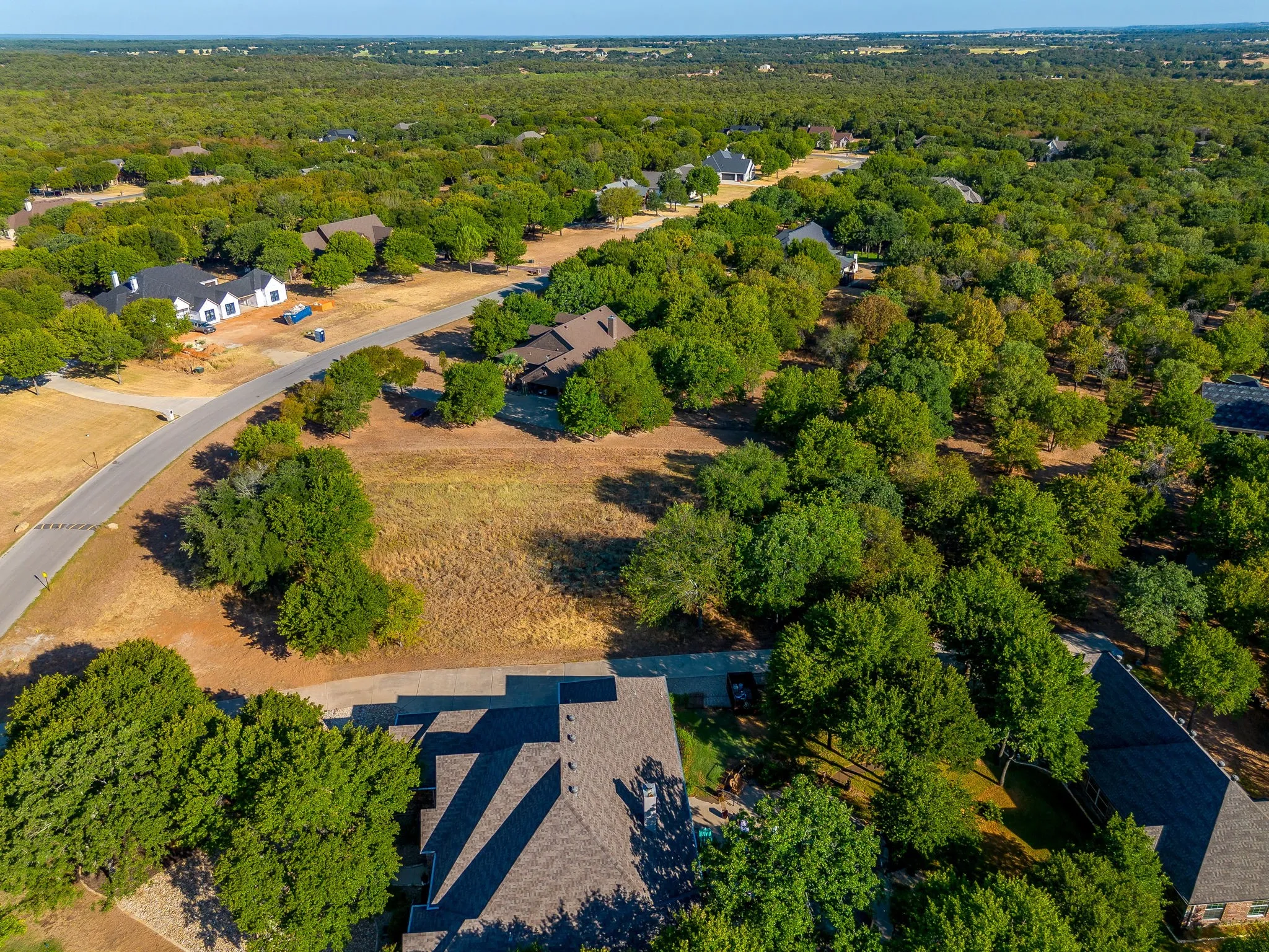 Expansive residential lot featuring mature trees and a paved road