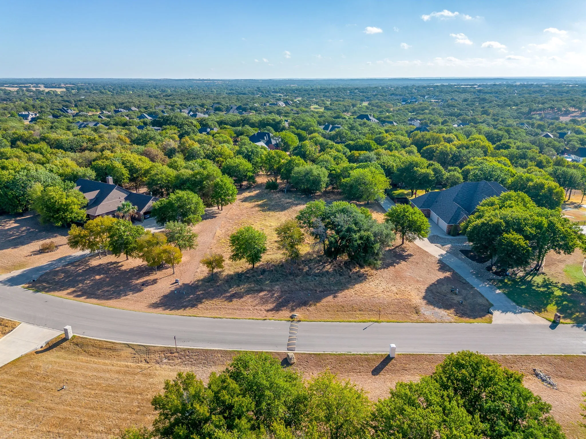 Expansive lot with mature trees and a paved driveway, set within a tree-lined neighborhood