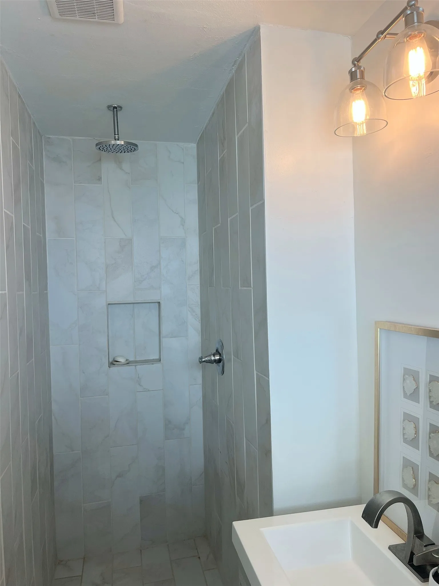Walk-in shower with vertical tile detailing, an integrated niche, and a ceiling-mounted rain showerhead
