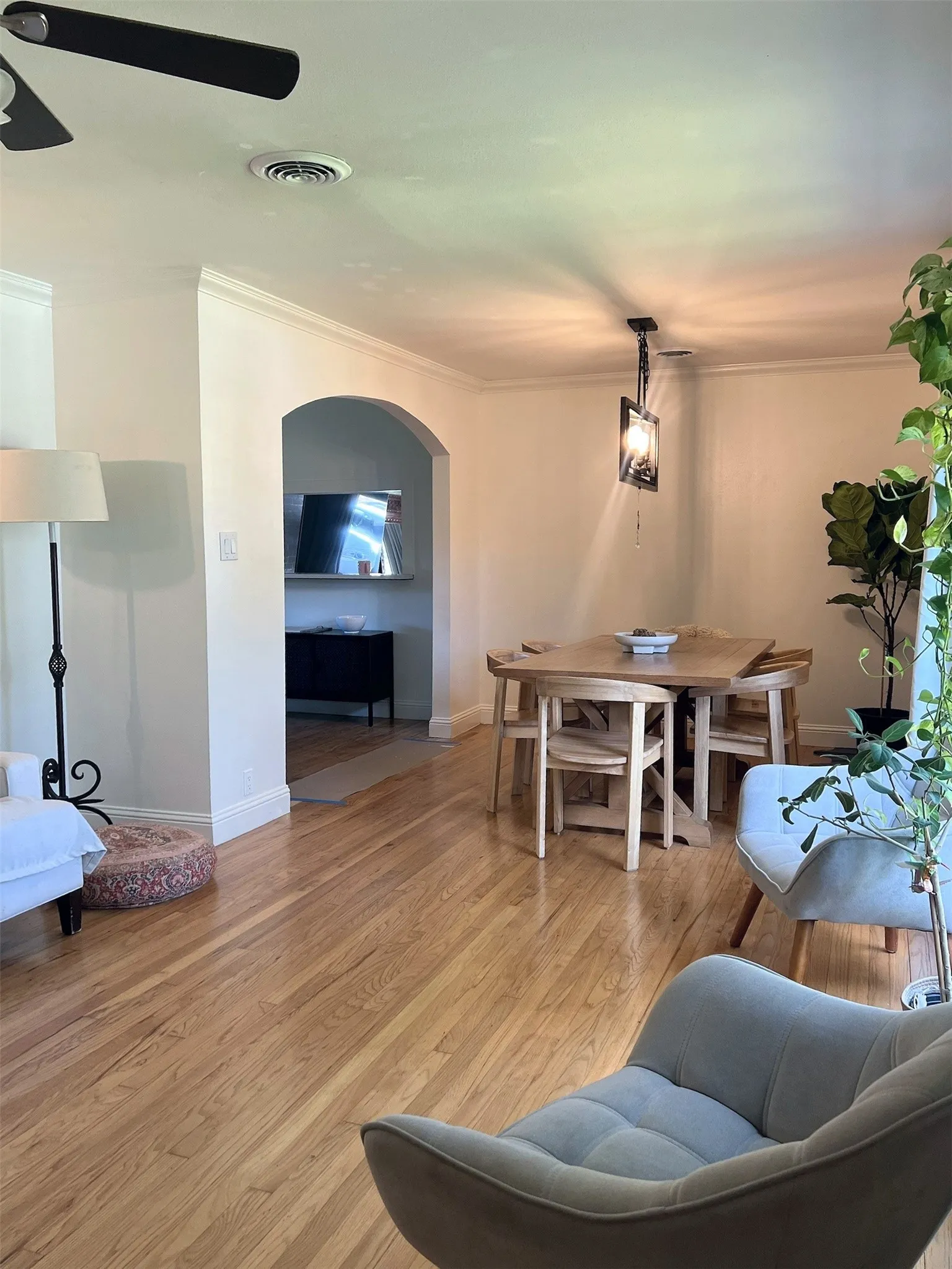 Hardwood flooring throughout, crown molding, arched passageway, and ceiling fan