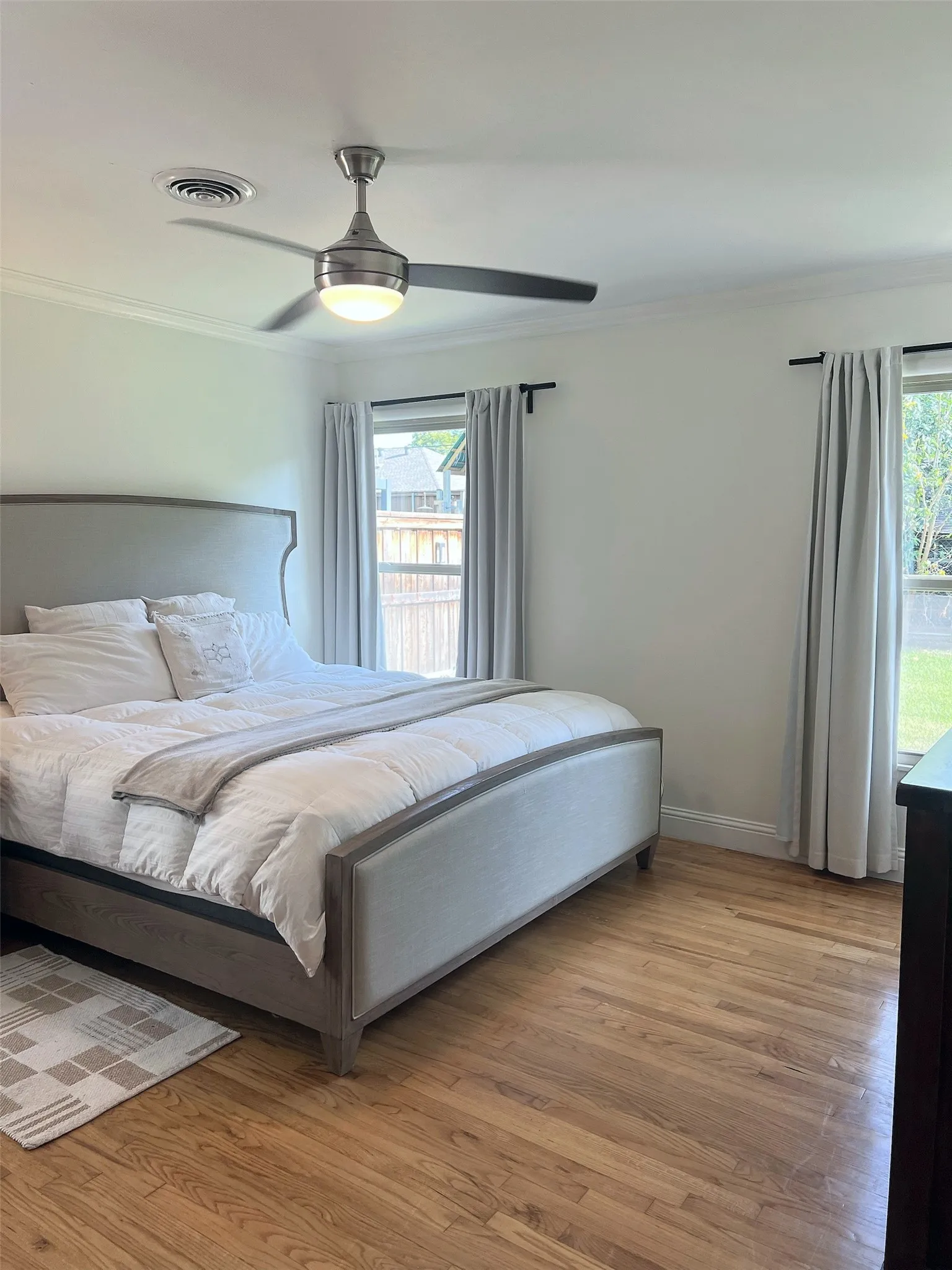 Hardwood flooring, crown molding, dual windows, and ceiling fan with integrated lighting