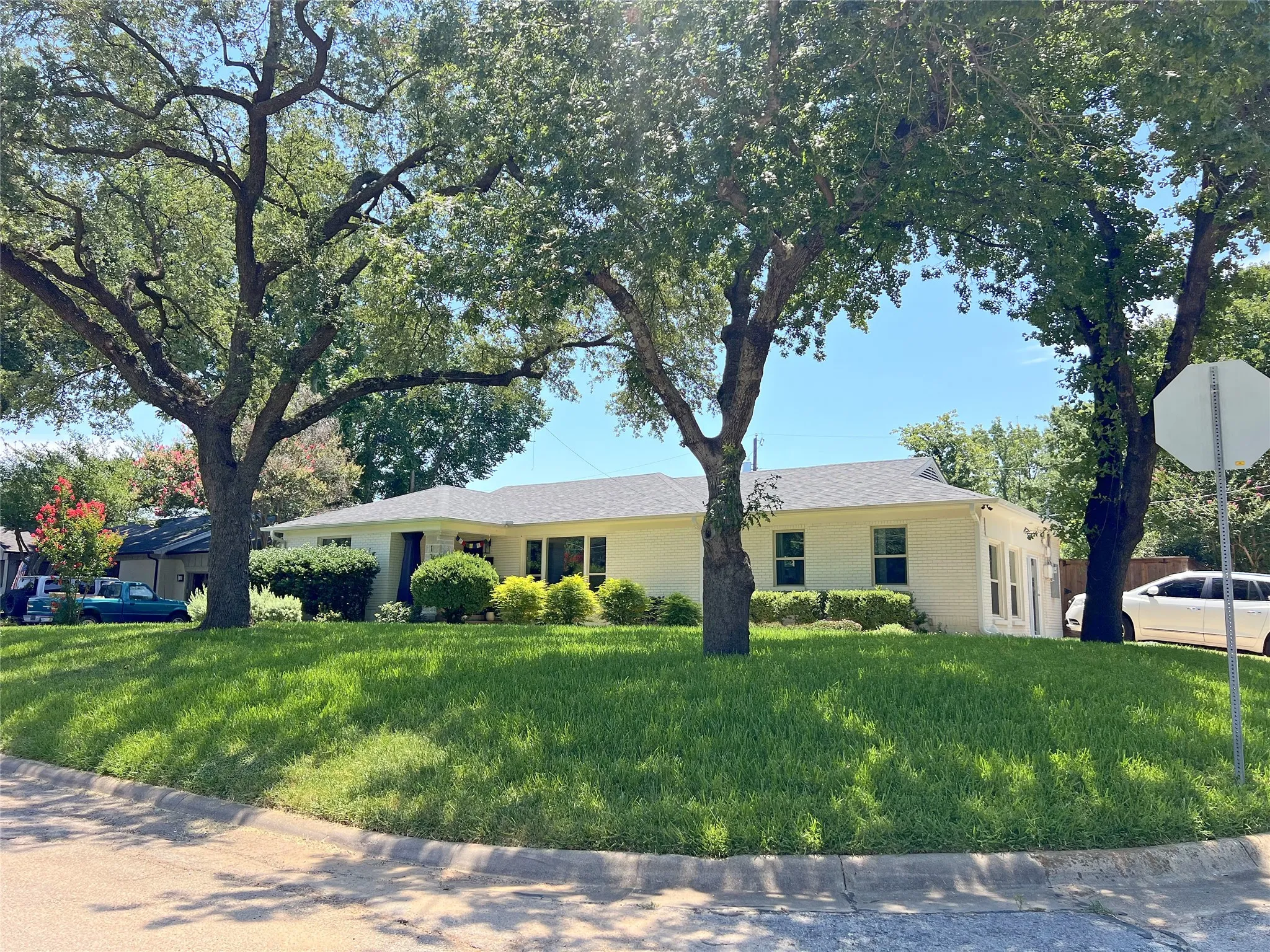 1200 Daisy, a white brick ranch home on a ~.22 acre lot with a ~5 year old roof and lush greenery