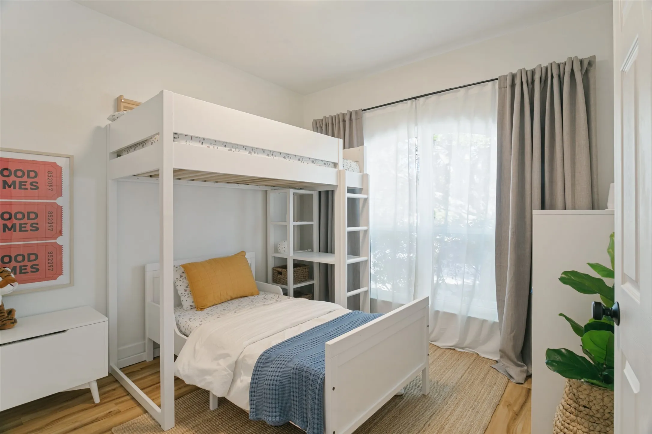 Wood-finish flooring, white walls, and a large window with sheer and blackout curtains