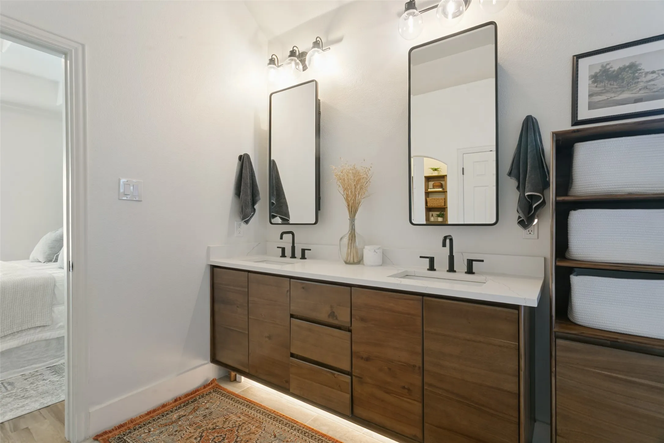 Double vanity with wood-finish cabinetry, white countertops, and matte black fixtures