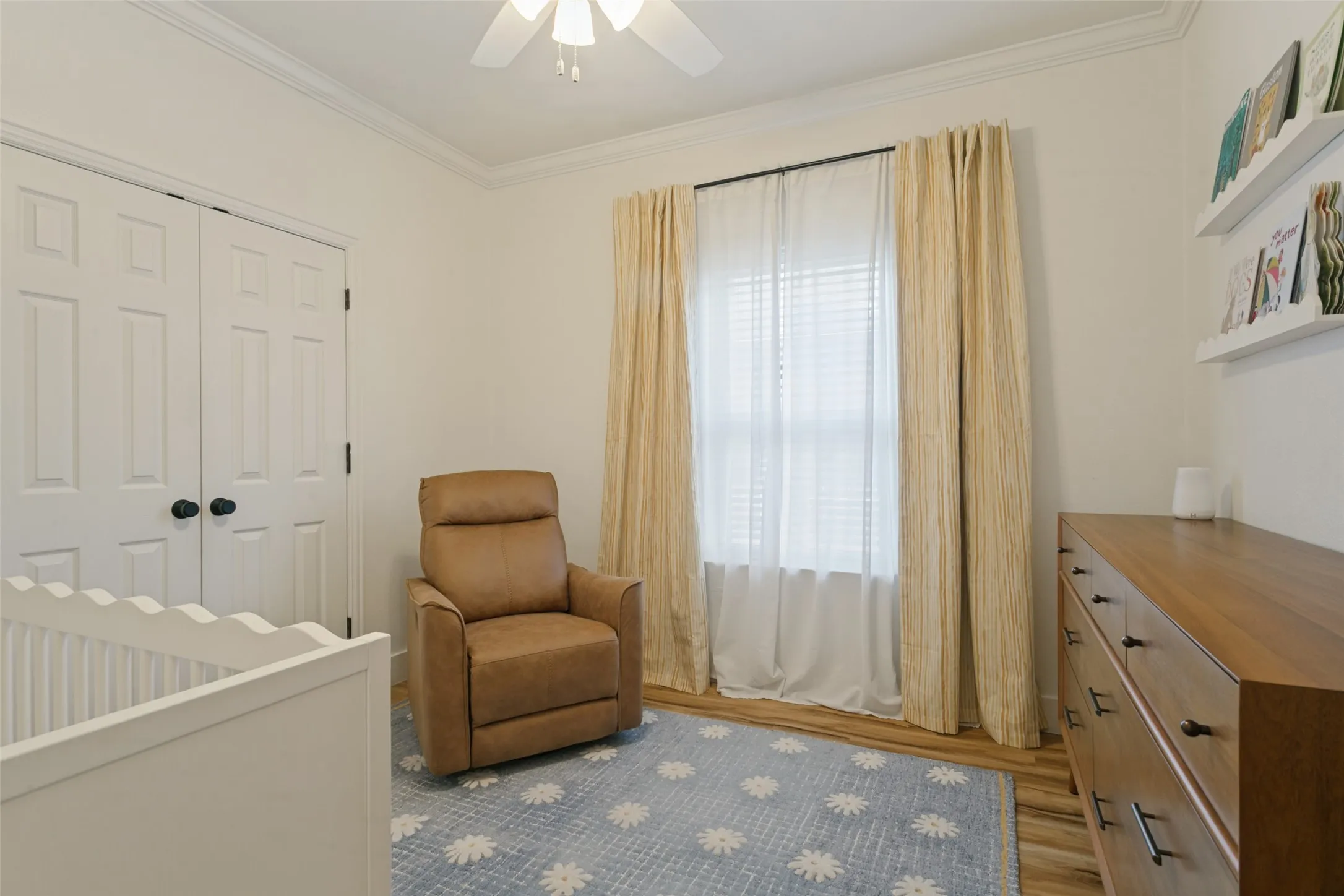 Wood-finish flooring, crown molding, and a ceiling fan with light fixture