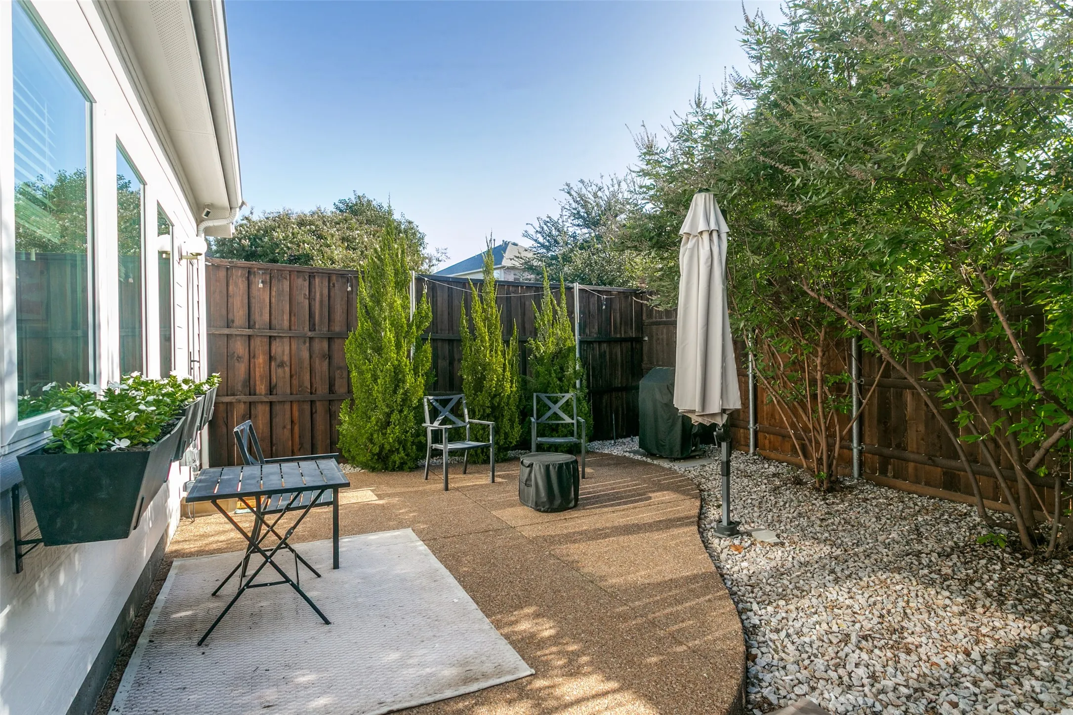 Private outdoor space featuring a textured patio, gravel landscaping, and perimeter fencing