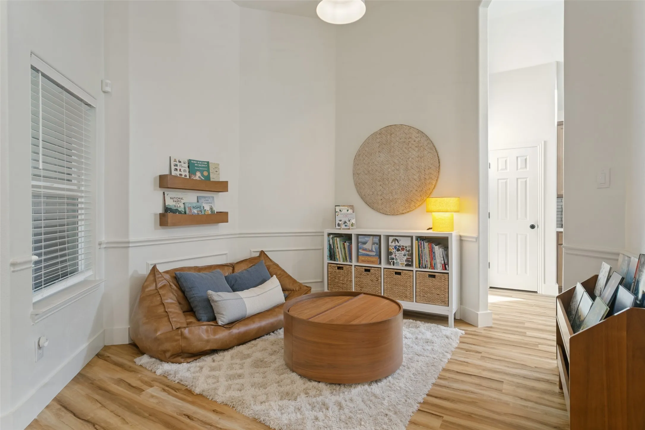 Light wood-finish flooring, white wall paneling, and a white interior door