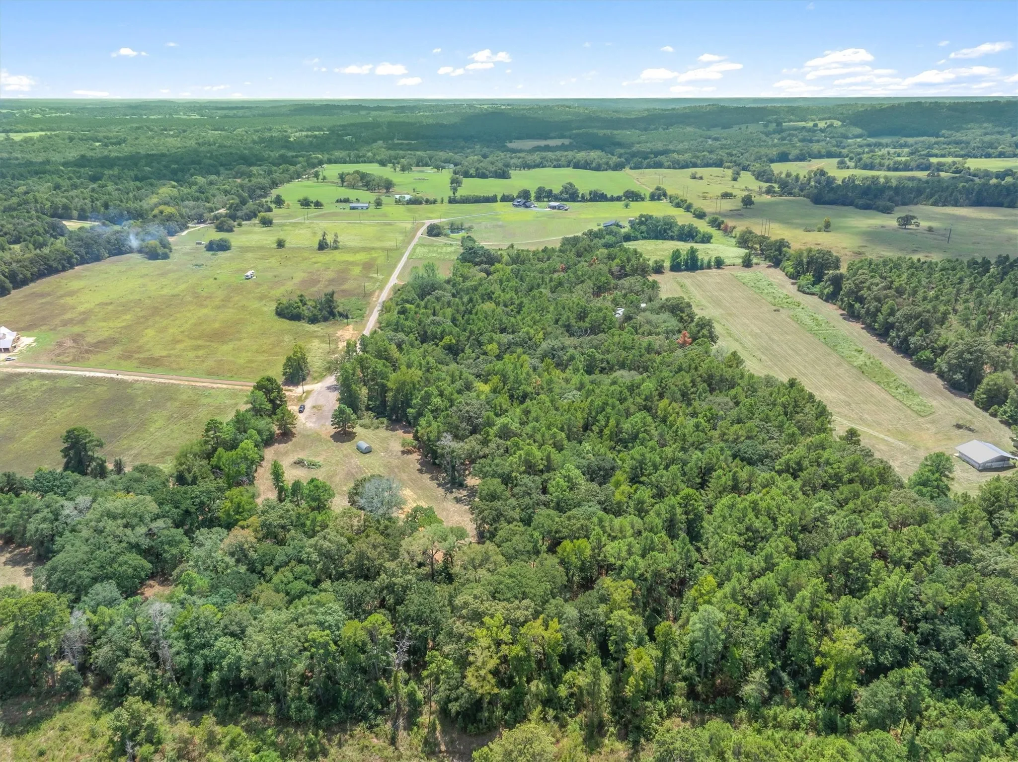 Expansive land offering a mix of wooded areas and open fields, including a cleared strip