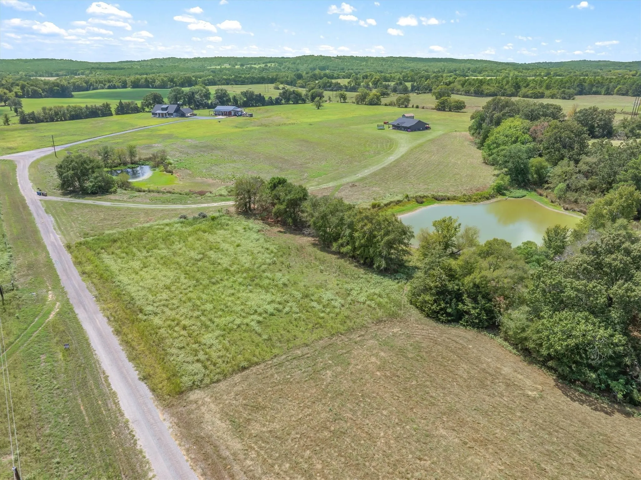 Extensive acreage featuring a gravel road, two distinct ponds, and scattered mature trees